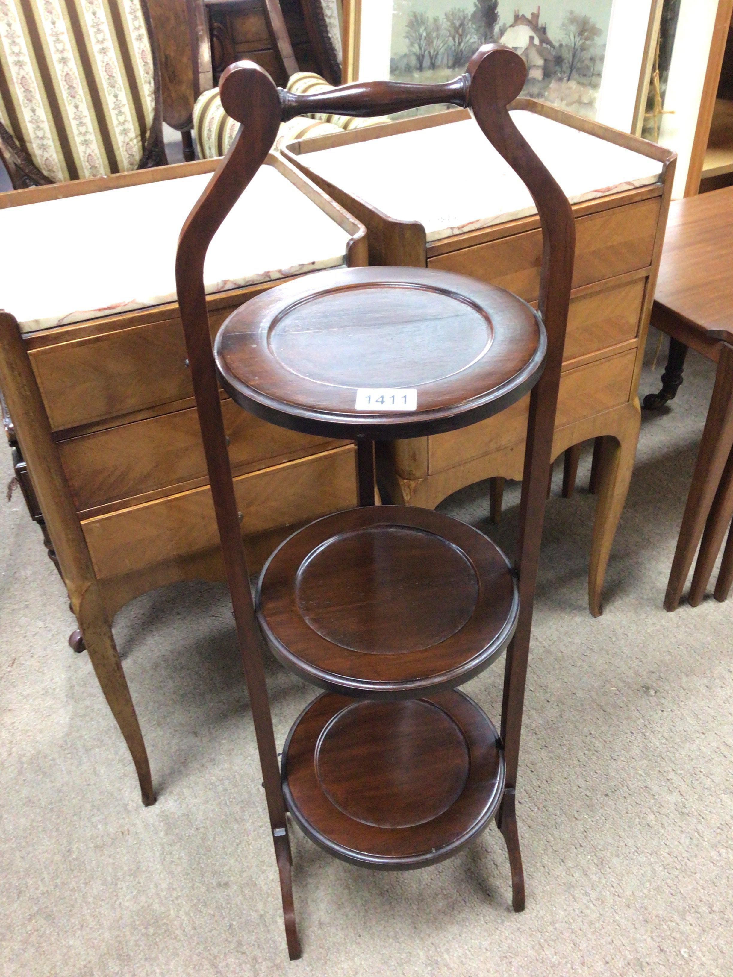 An Edwardian mahogany three tier cake stand shaped handle and folding round tiers. NO RESERVE