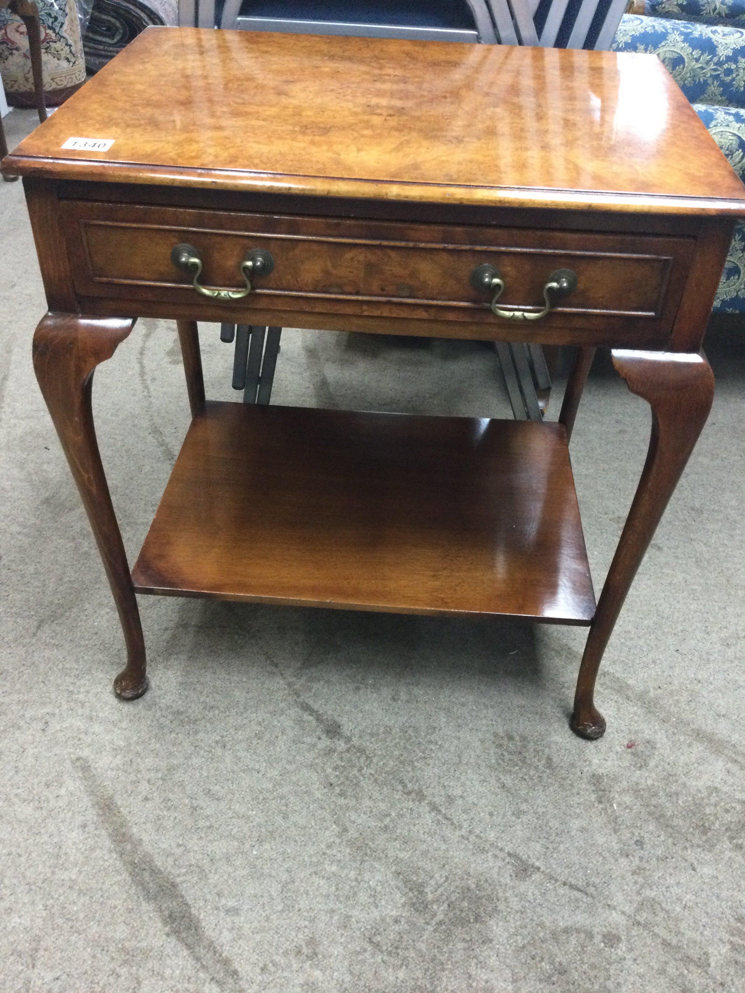 A walnut side table with single drawer on cabriole legs .