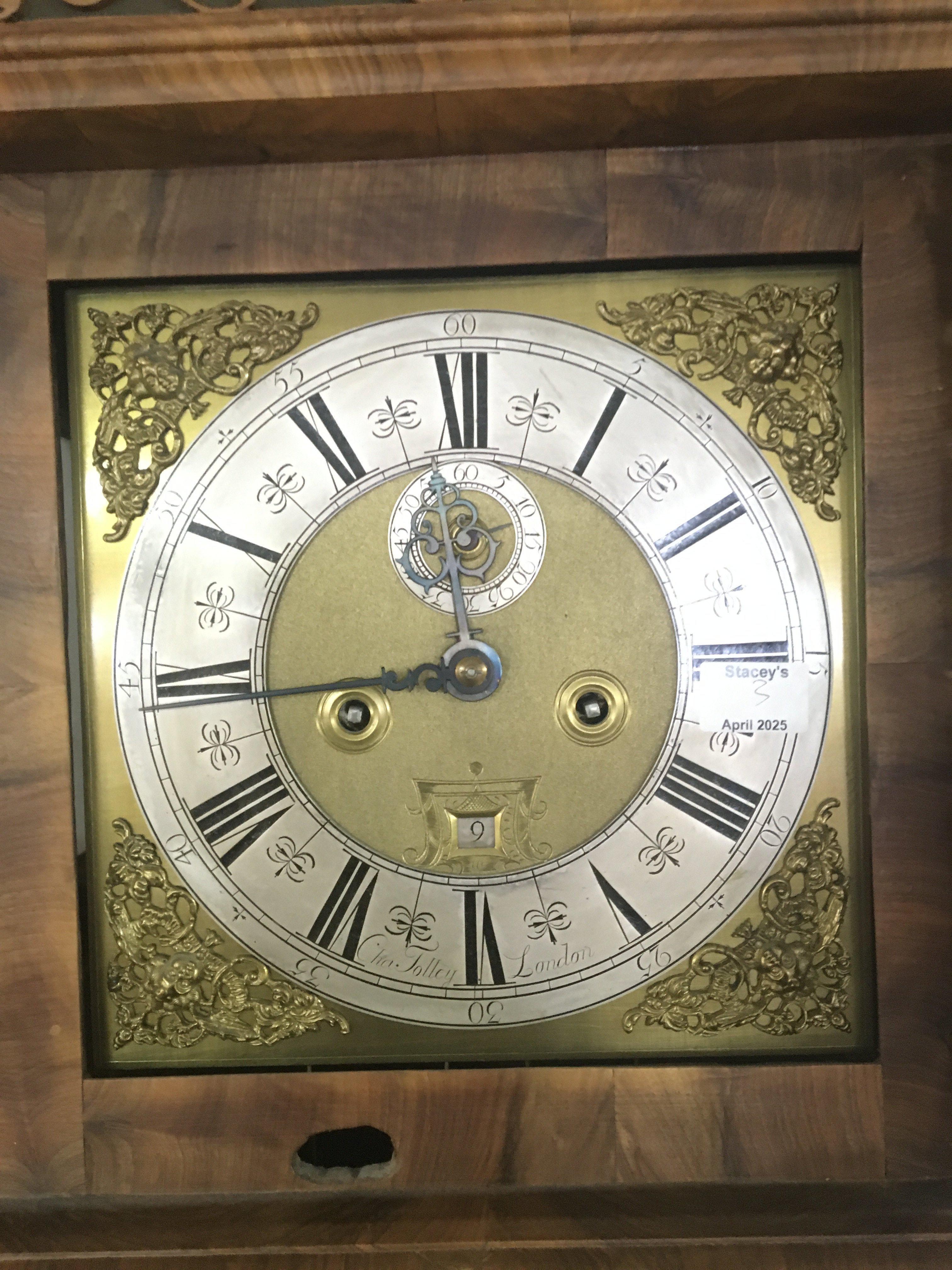 An Early 18th century figured walnut long case clock with a brass dial and silvered chapter ring maker Cha Tolley London. With date aperture and second subsidiary dial. Eight day going with pendulum and weights the case hood with barley twist pillars with a circular glass panel to the door. The clock restored and in appearing in good condition height 215cm