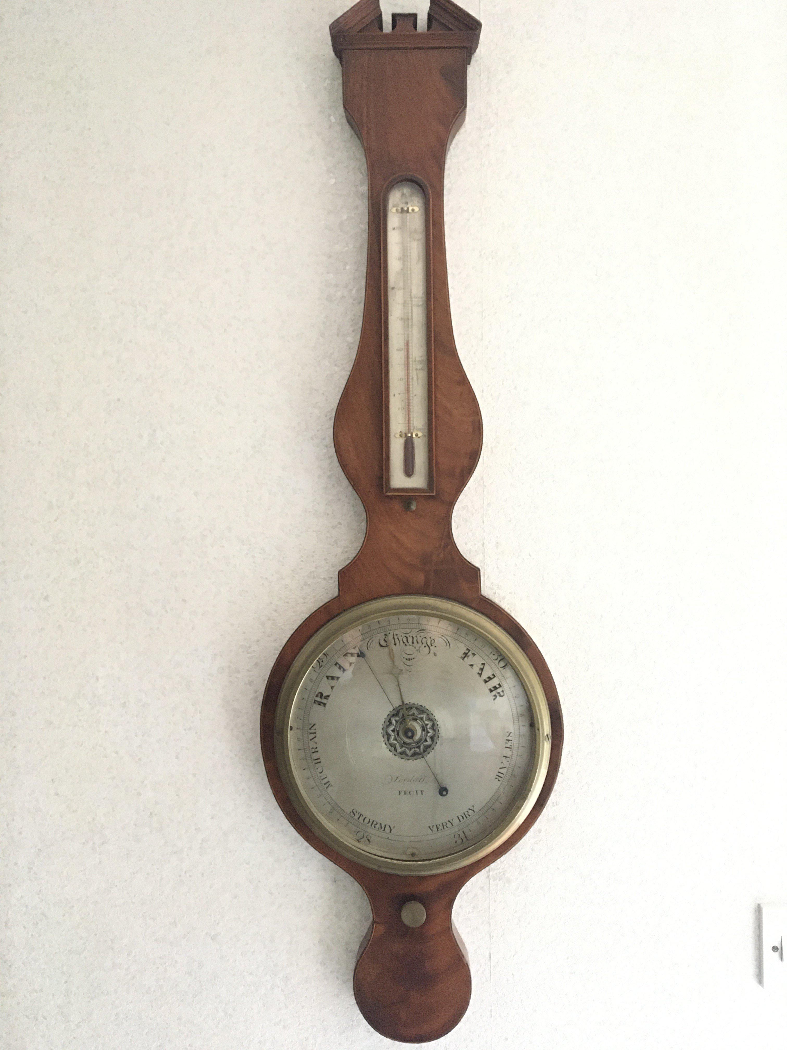 A George lV mahogany and boxwood banjo barometer with a silvered dial and thermometer box.