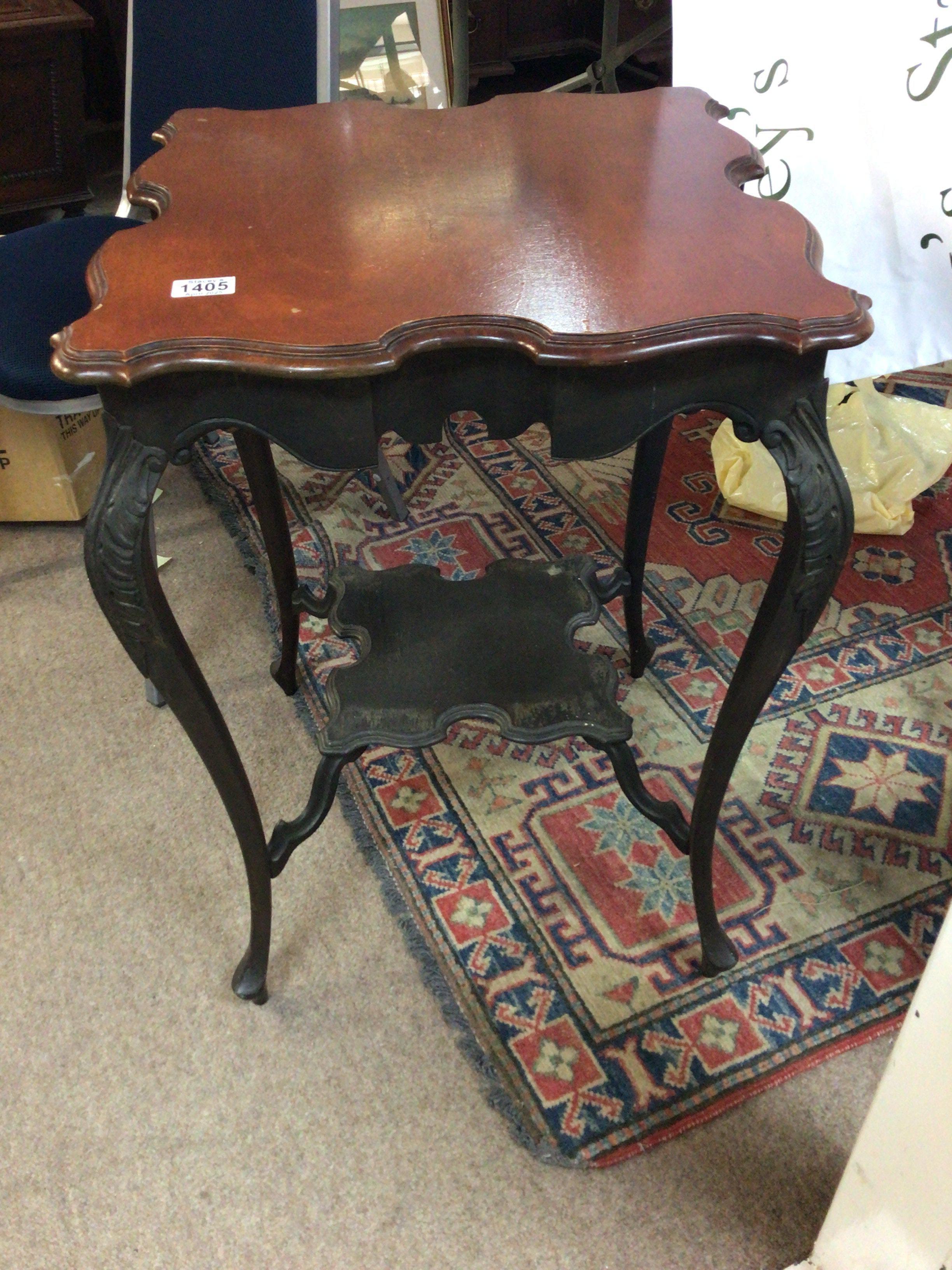 An Edwardian walnut occasional table with a shaped top and legs United bu an under shelf.