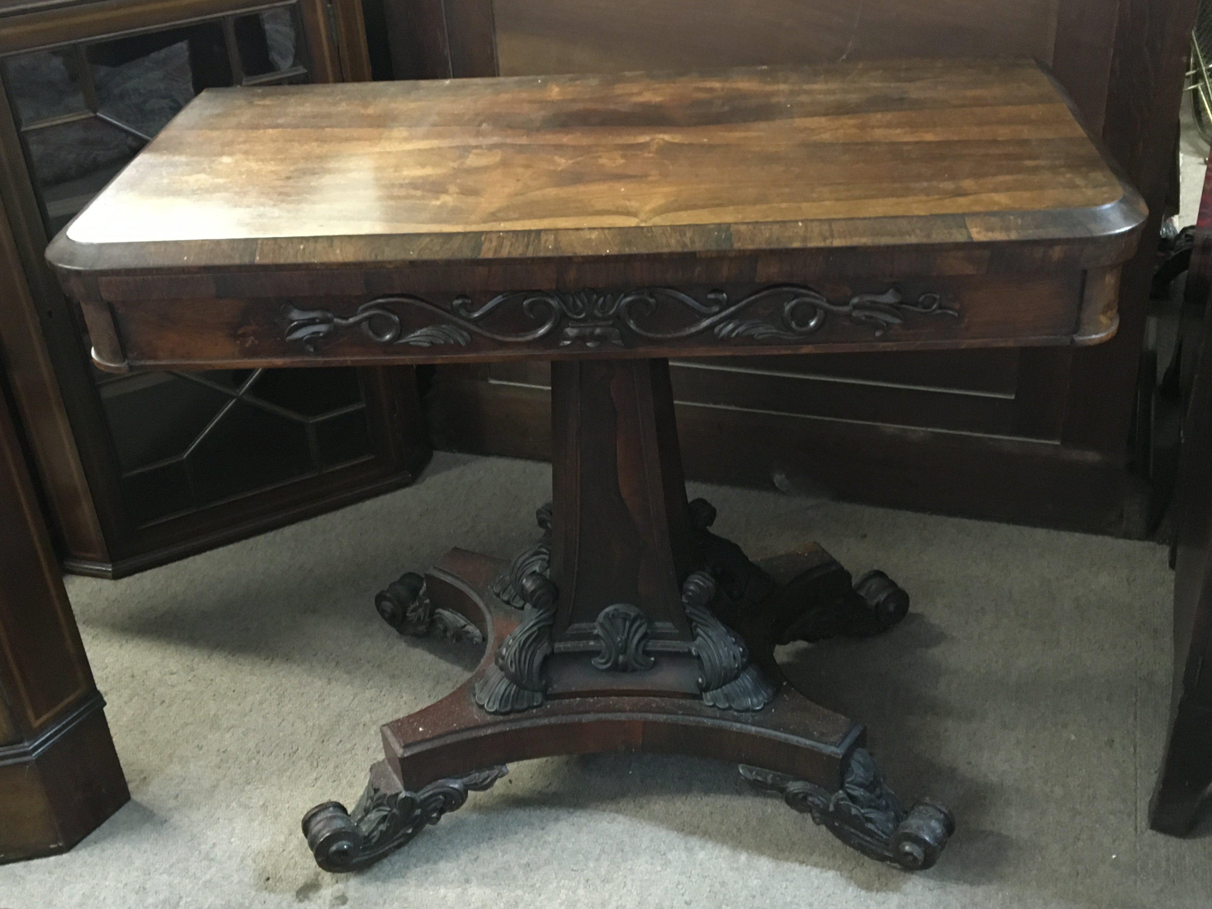 An early William IV rosewood tea table the hinged top above a frieze with applied mouldings the shaped column base with corner scrolls and conforming scroll feet.