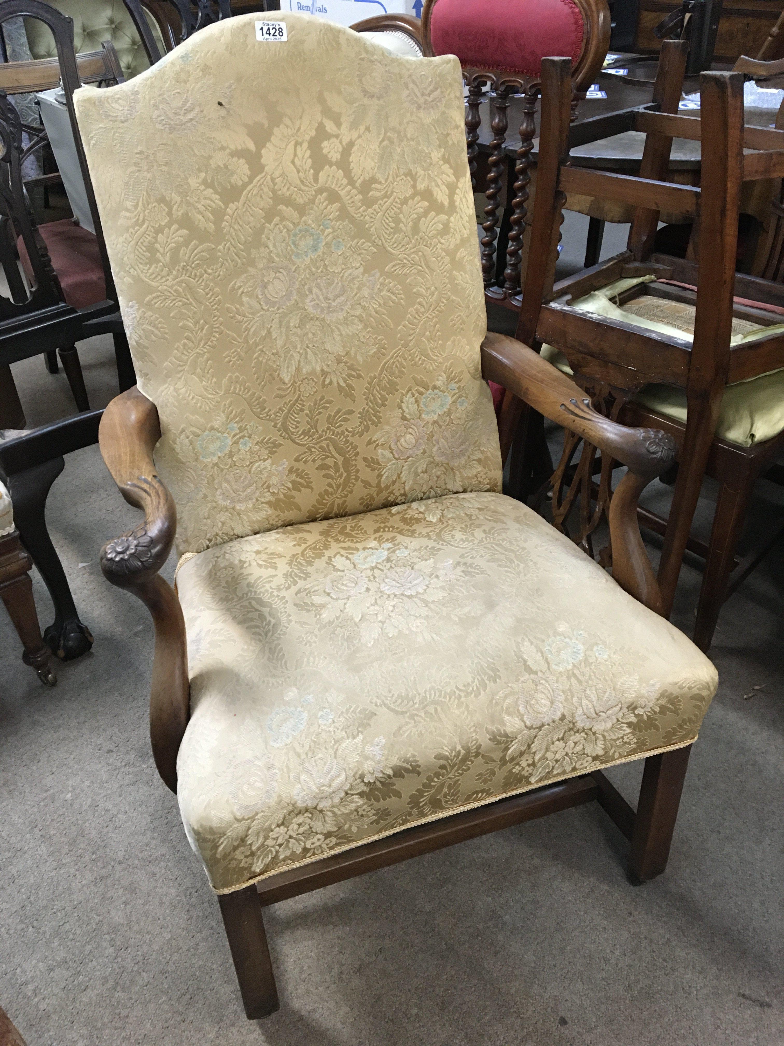 A George III Mahogany open arm chair with an upholstered seat and back with carved open arms with floral motifs on square legs united by stretches.