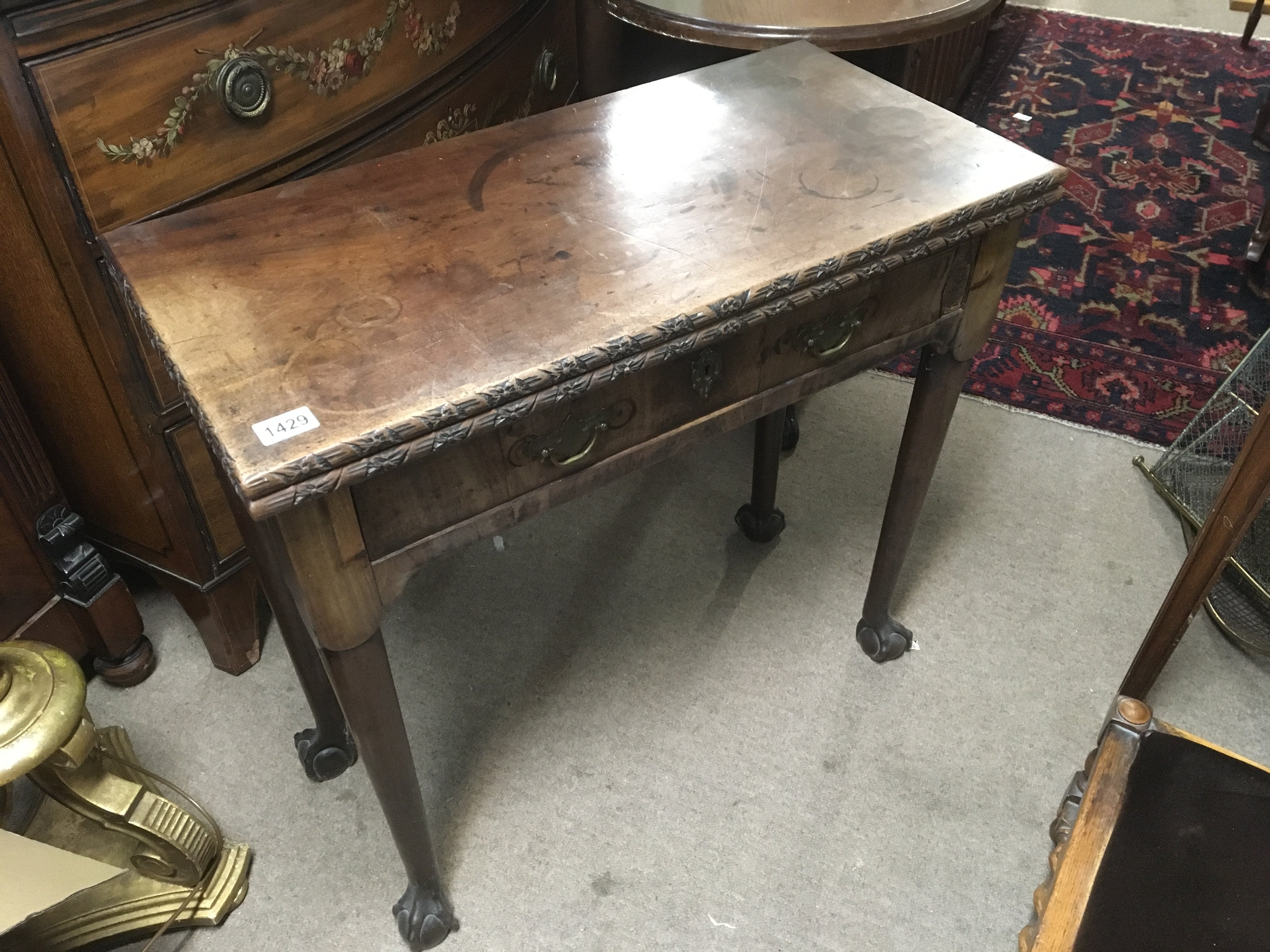 A George III mahogany tea table with a twin flap top above single drawer on tapering legs and ball and claw feet.
