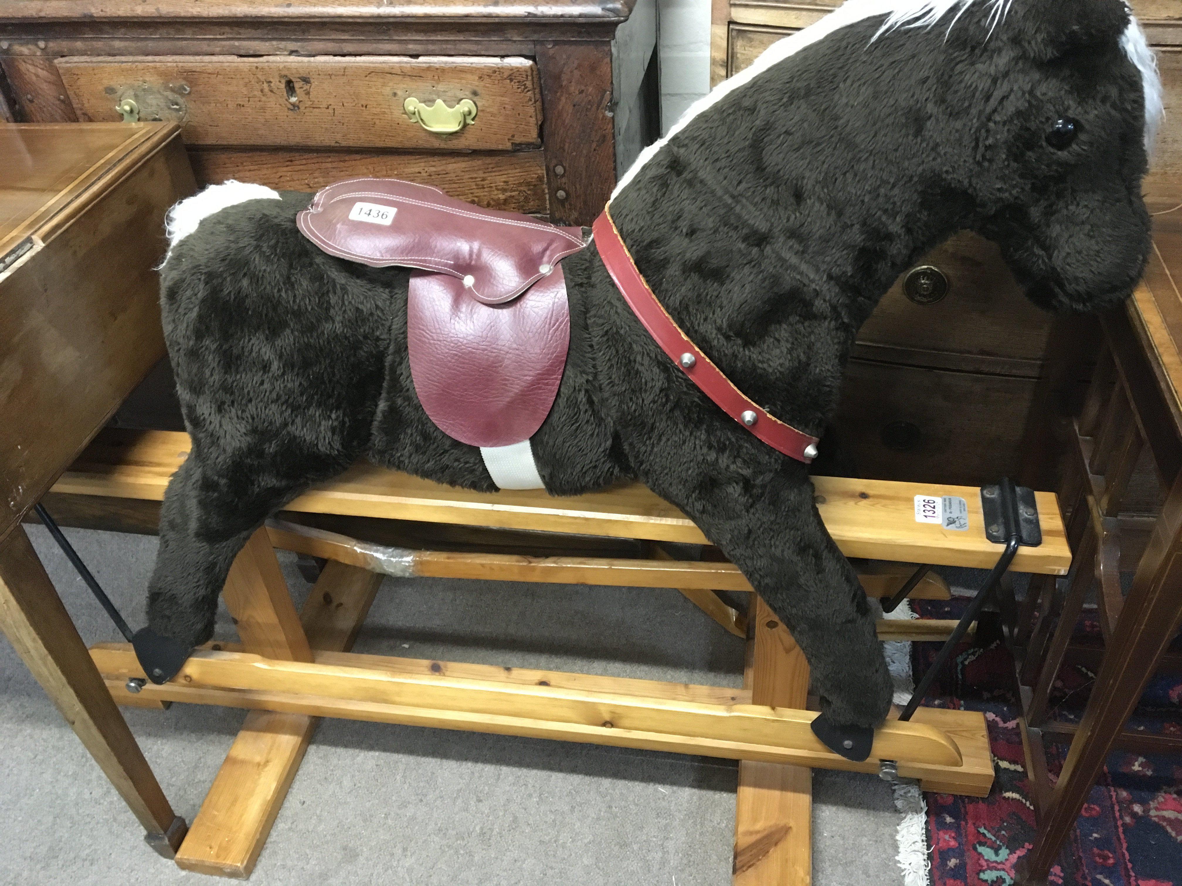 A fabric and wood rocking horse on a pine base.