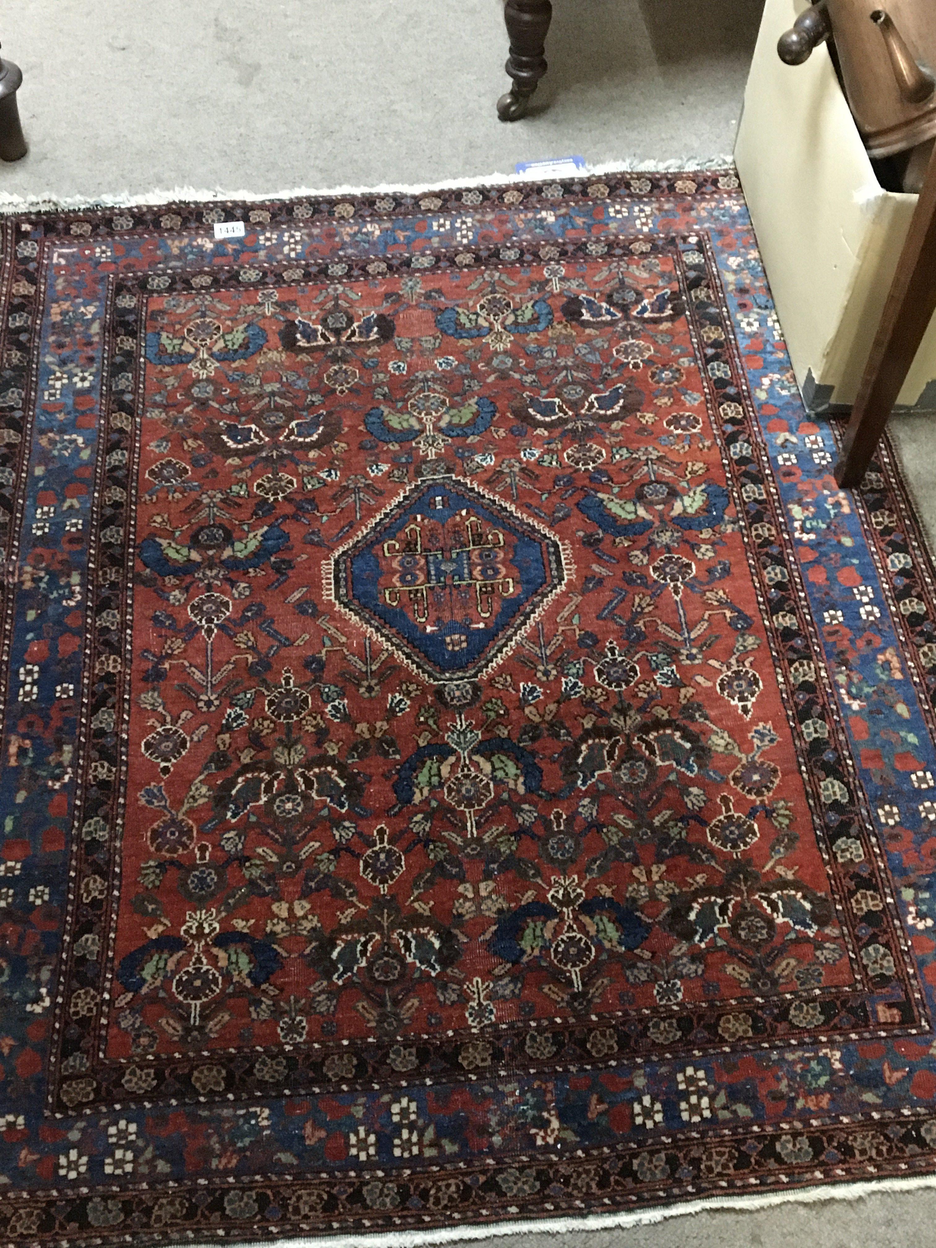 A small early 20th century hand Knotted rug with a floral pattern on a red field 132x136cm
