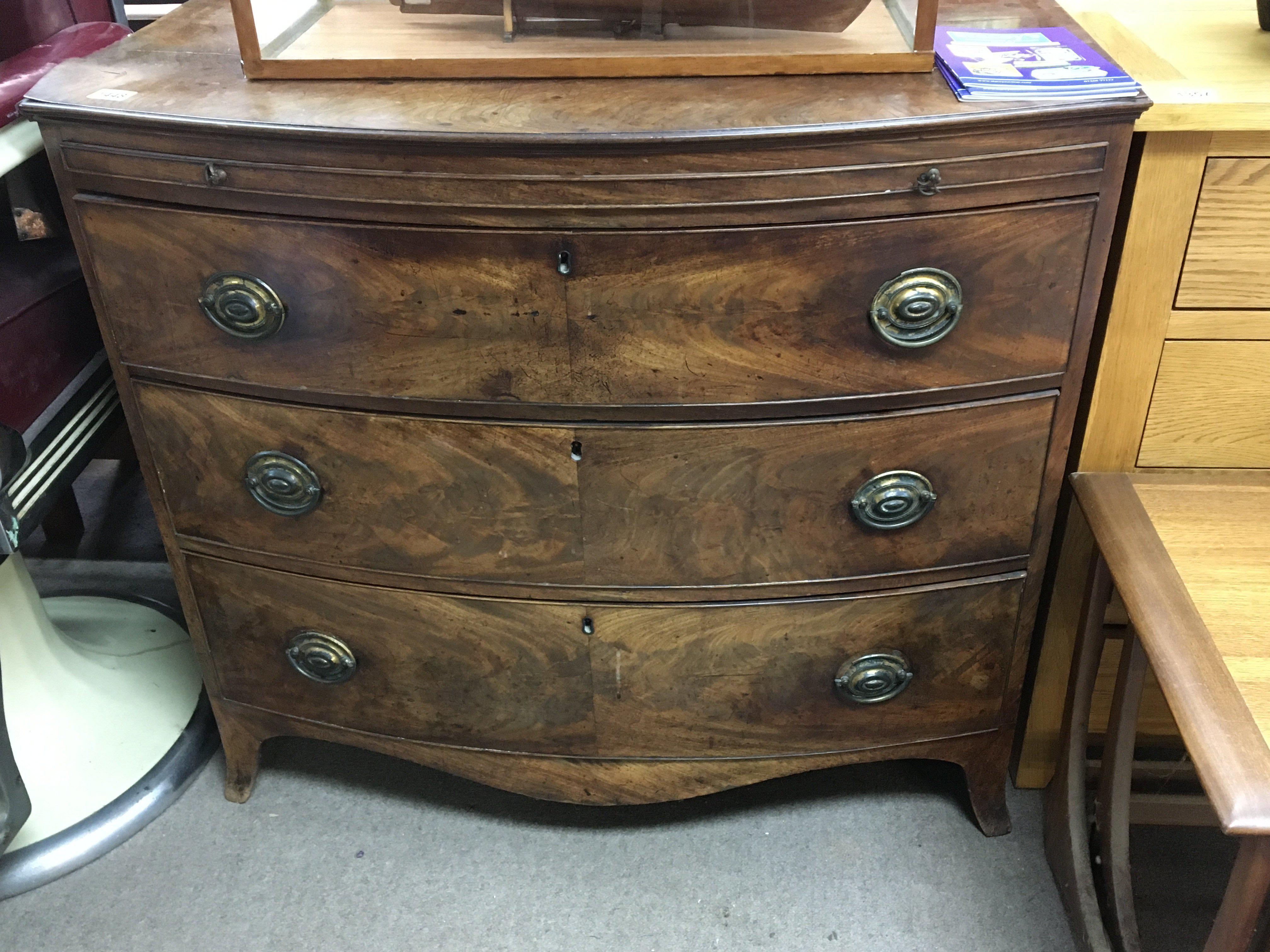 A late George III mahogany bow fronted chest of drawers fitted with a brushing slide above three drawers on swept bracket feet. 101cm long.