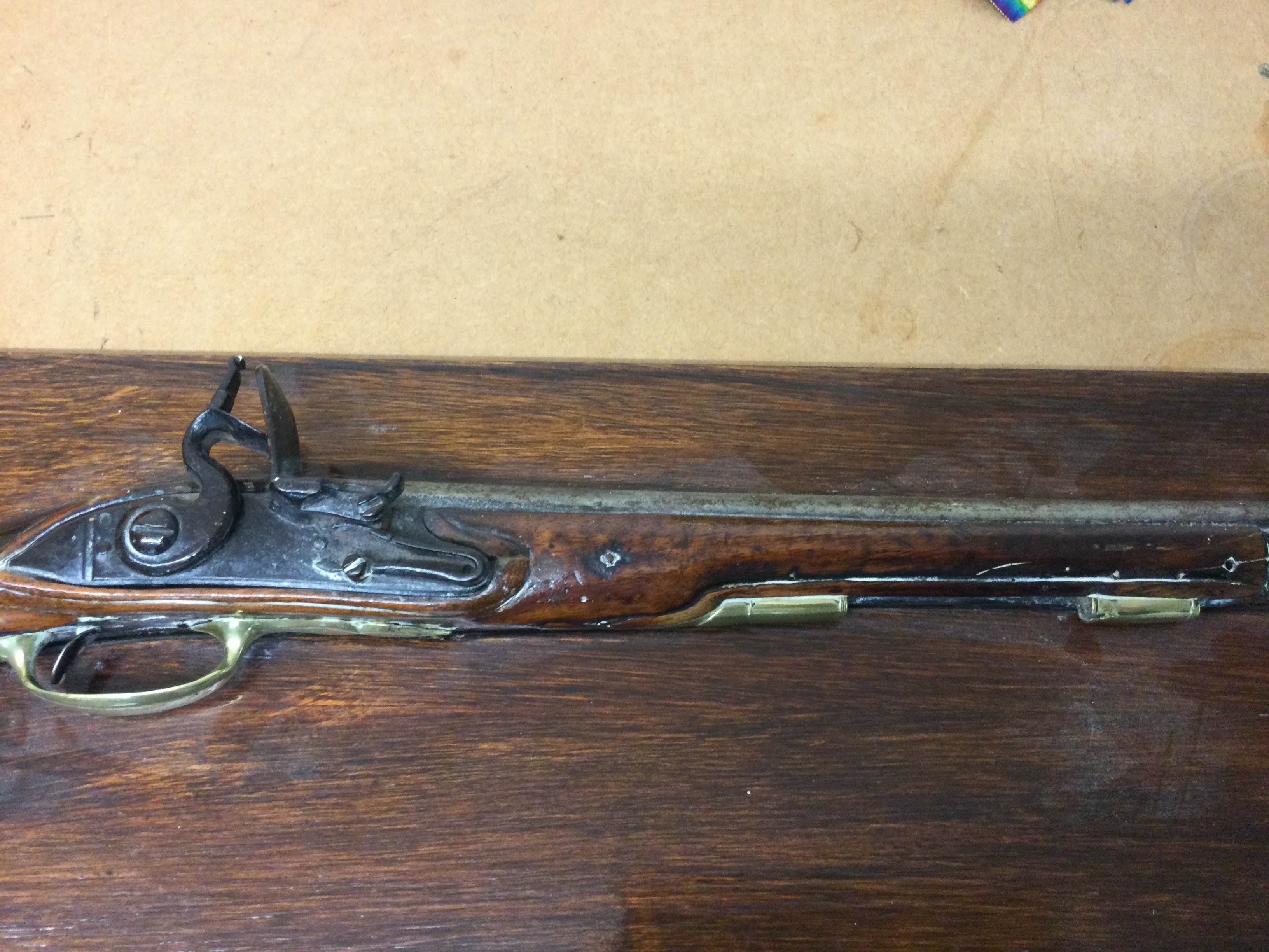 A flintlock pistol with brass mounts fitted in a mahogany plaque .
