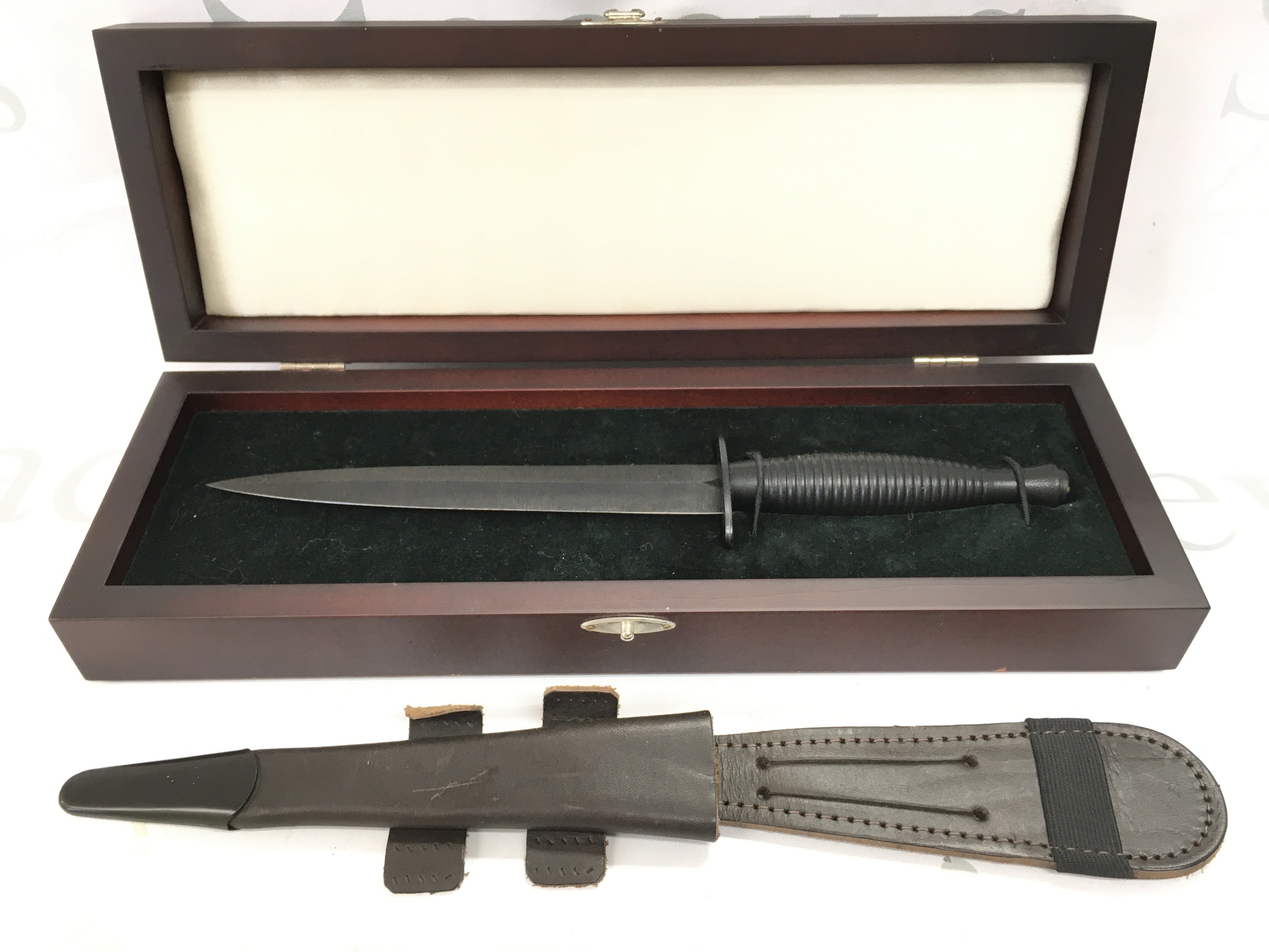 A cased Fairbairn Sykes design fighting knife with a leather scabbard. Knife 29cm long , blade 17cm long.