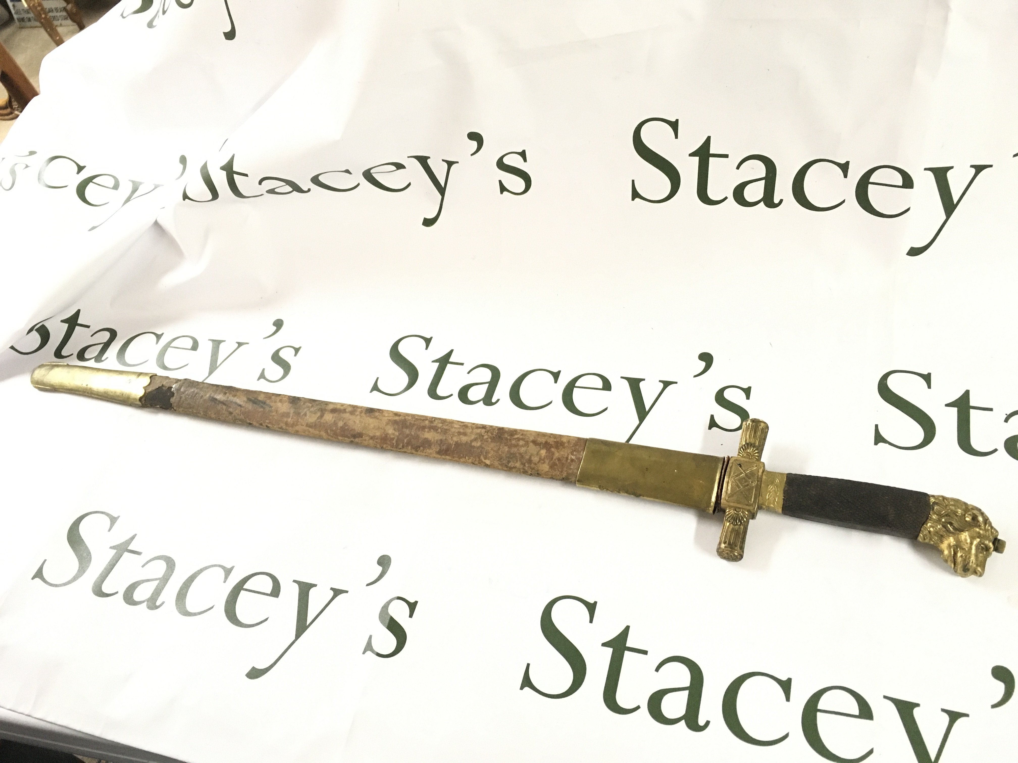 An unusual short sword with a gilt lions head pommel, leather and gilt scabbard. Scabbard is stuck to the blade . 75cm total length