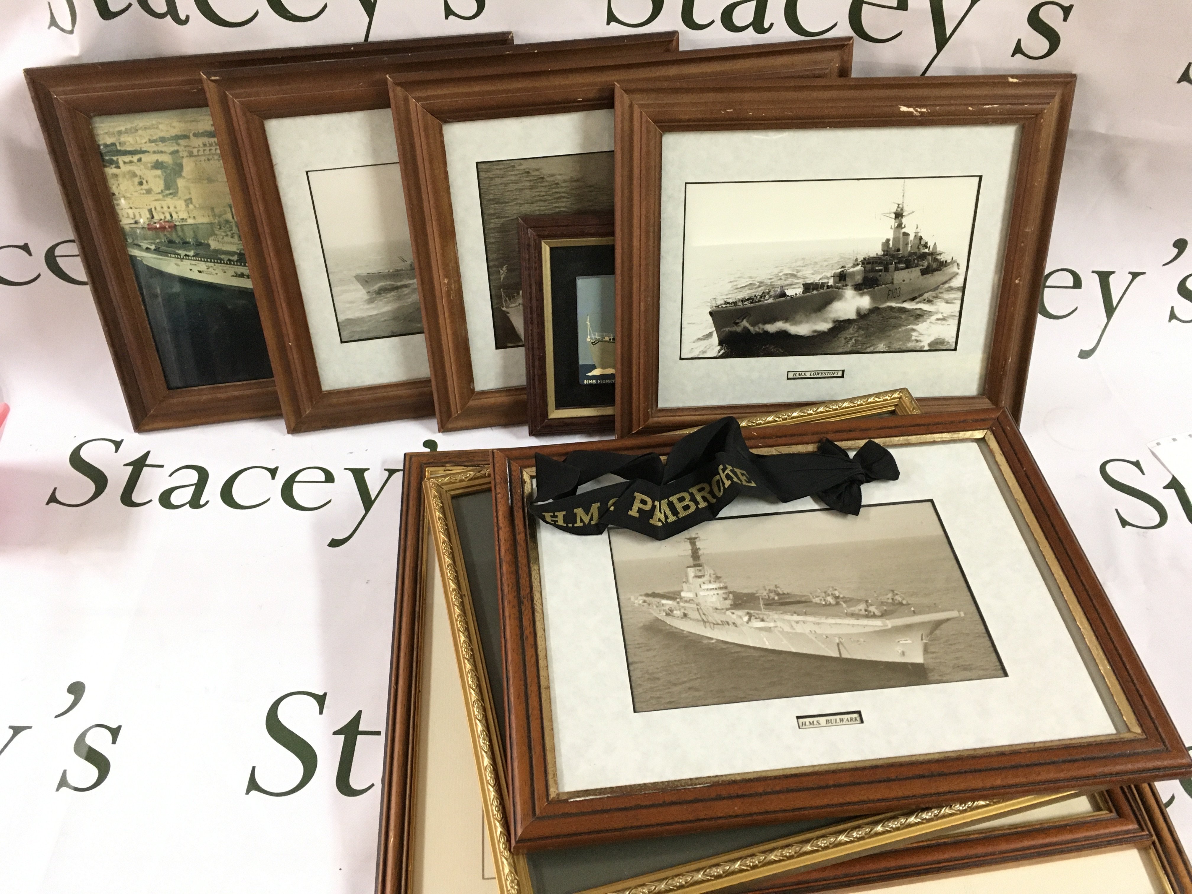 A Collection of framed photos including battle ships and a collection of cap tallys