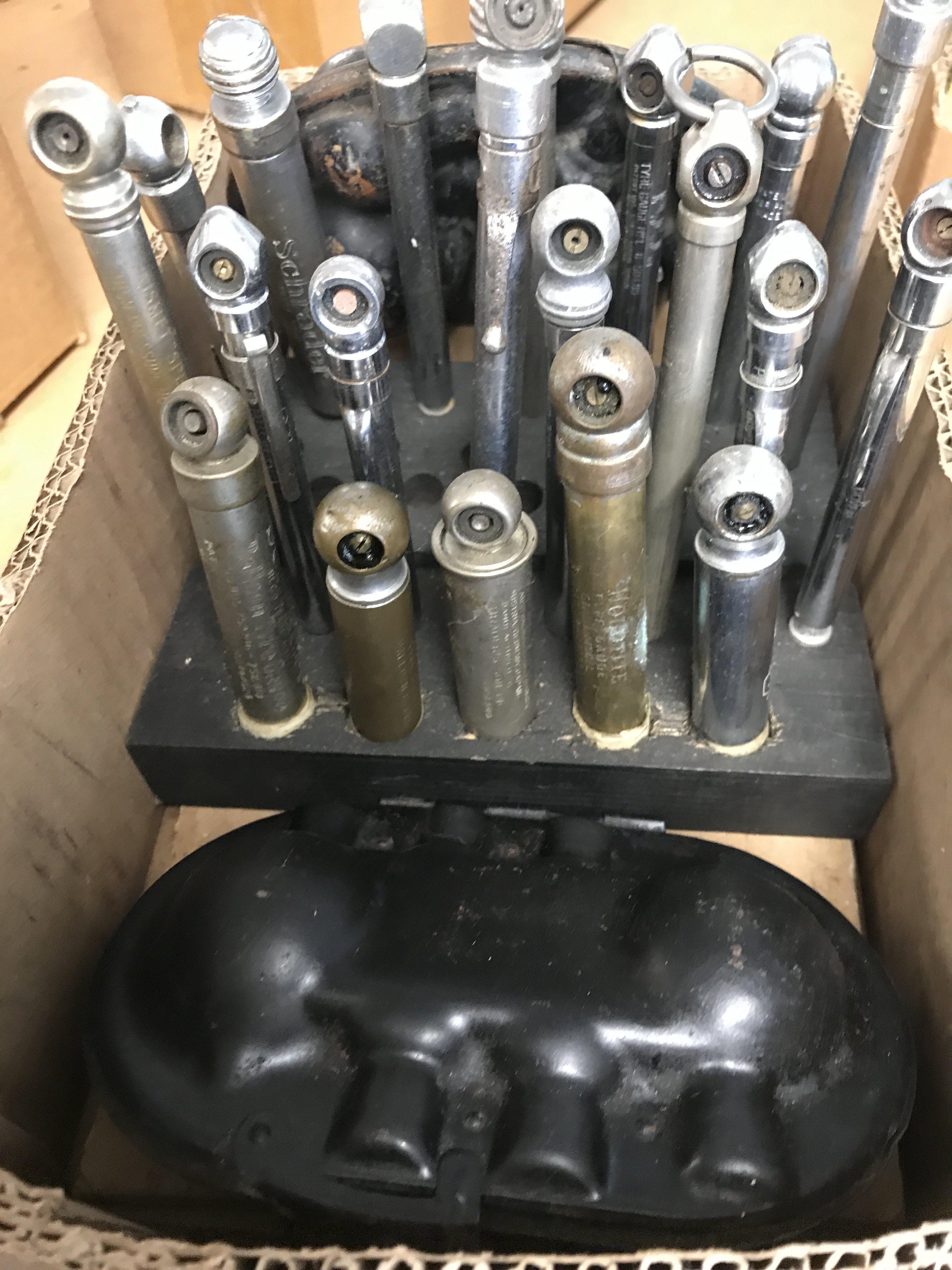 Two small wooden stands holding 20 vintage tyre pressure gauges and 2 car bulb holders