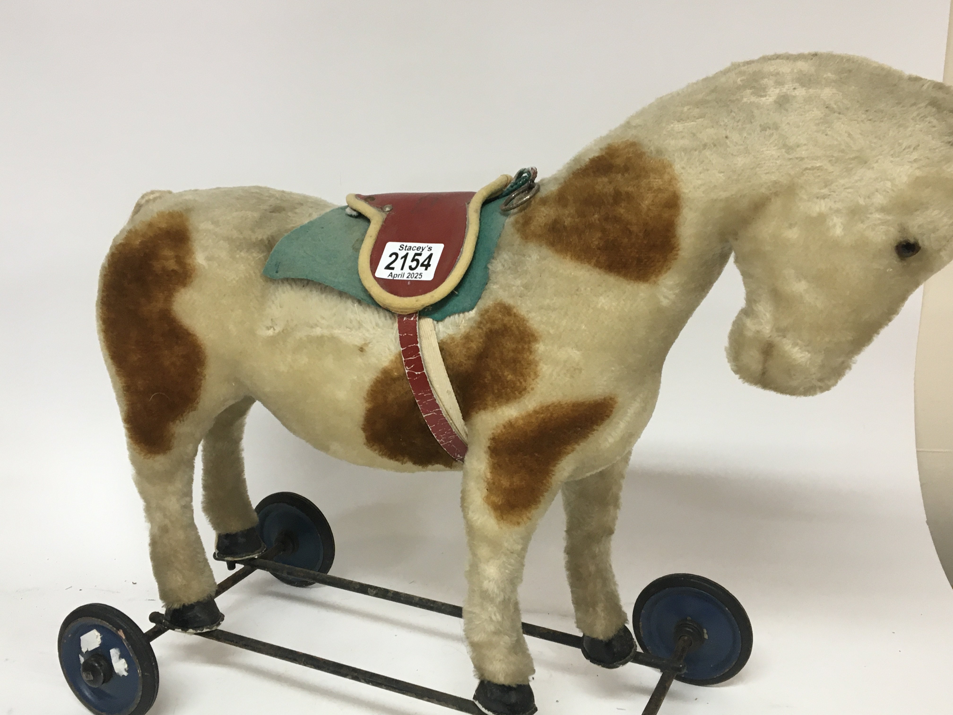 A Vintage pull along horse with pull cord and red saddle.