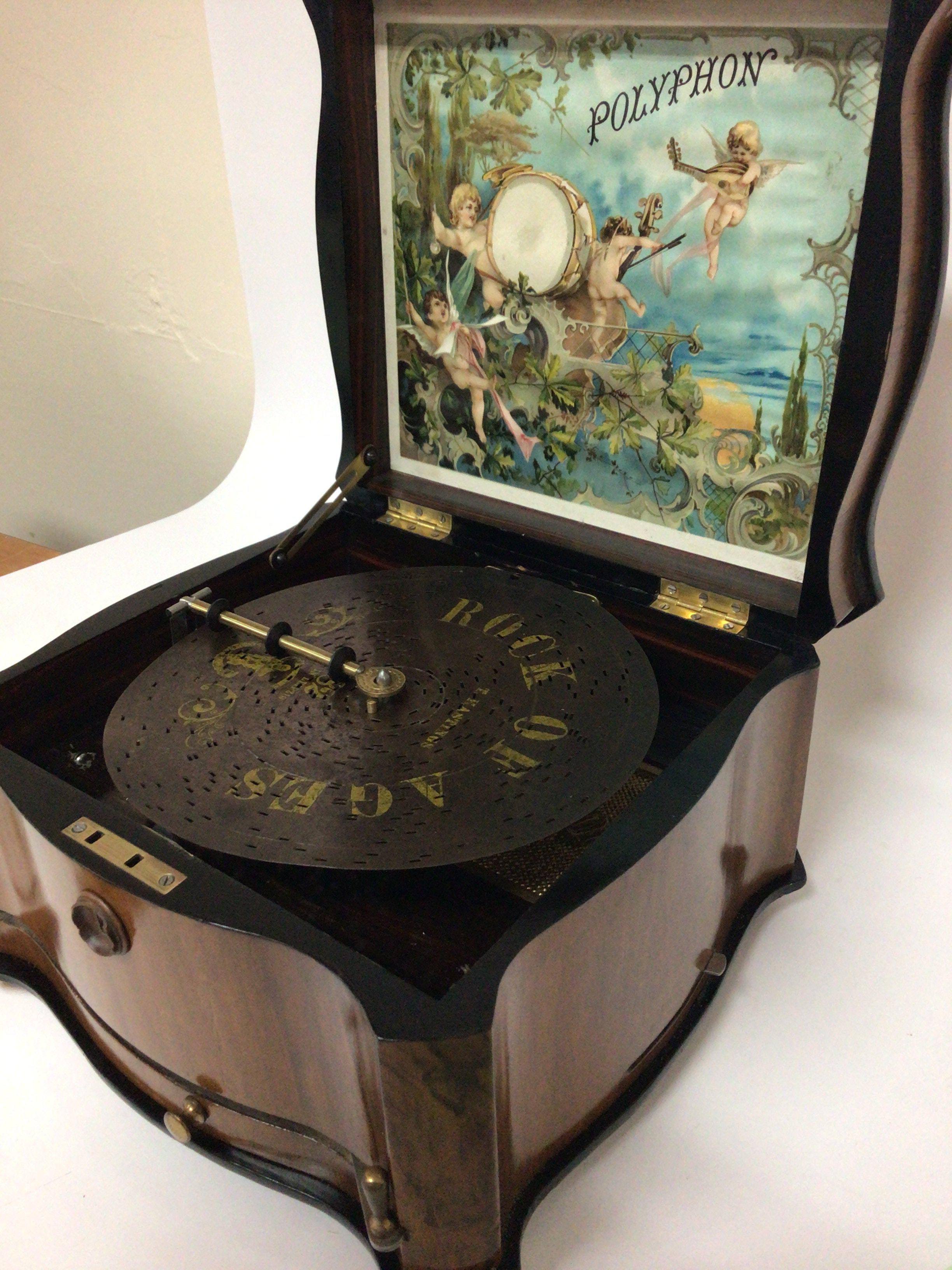 A late 19th century Continental walnut cased Polyphon in very good condition the shaped case with a hinged lid enclosing a coloured lithograph with musical cherubs. The movement a style 41 lever wound 20cm discs seen working and with additional discs.
