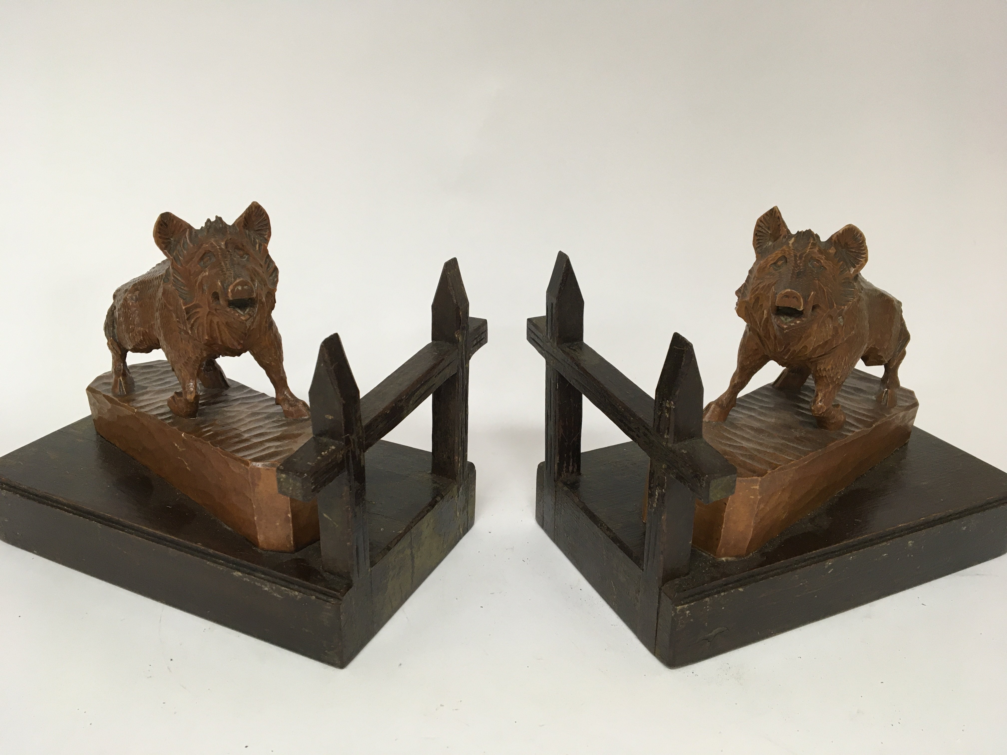 A pair of carved wood Black Forest bookends in the form of wild boar on gate post bases length 24cm