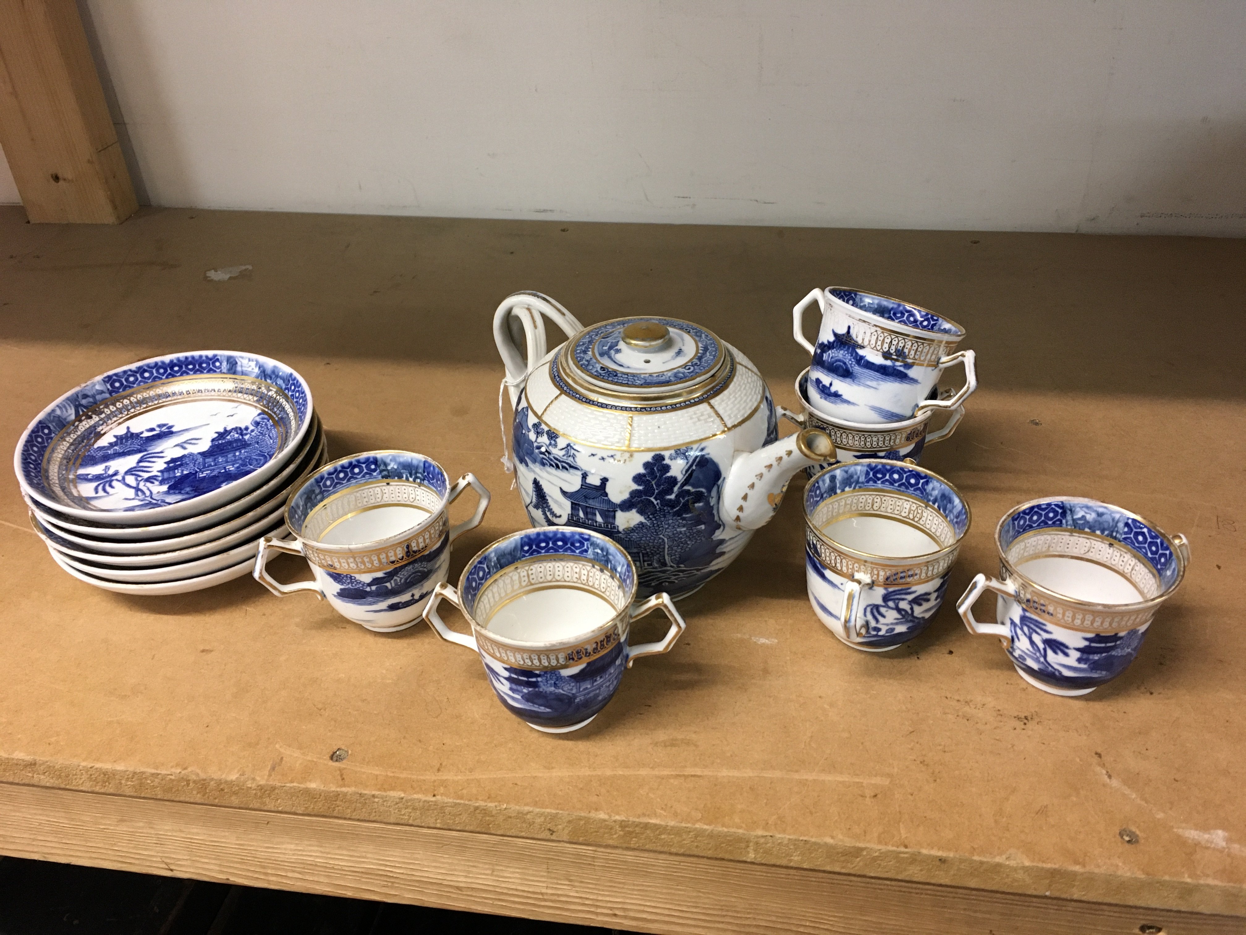 A Chinese 18th century Tea set decorated with lakeside pagodas in underglaze blue. Featuring plates, twin handled cups and a (damaged and restored) tea pot. This lot cannot be posted