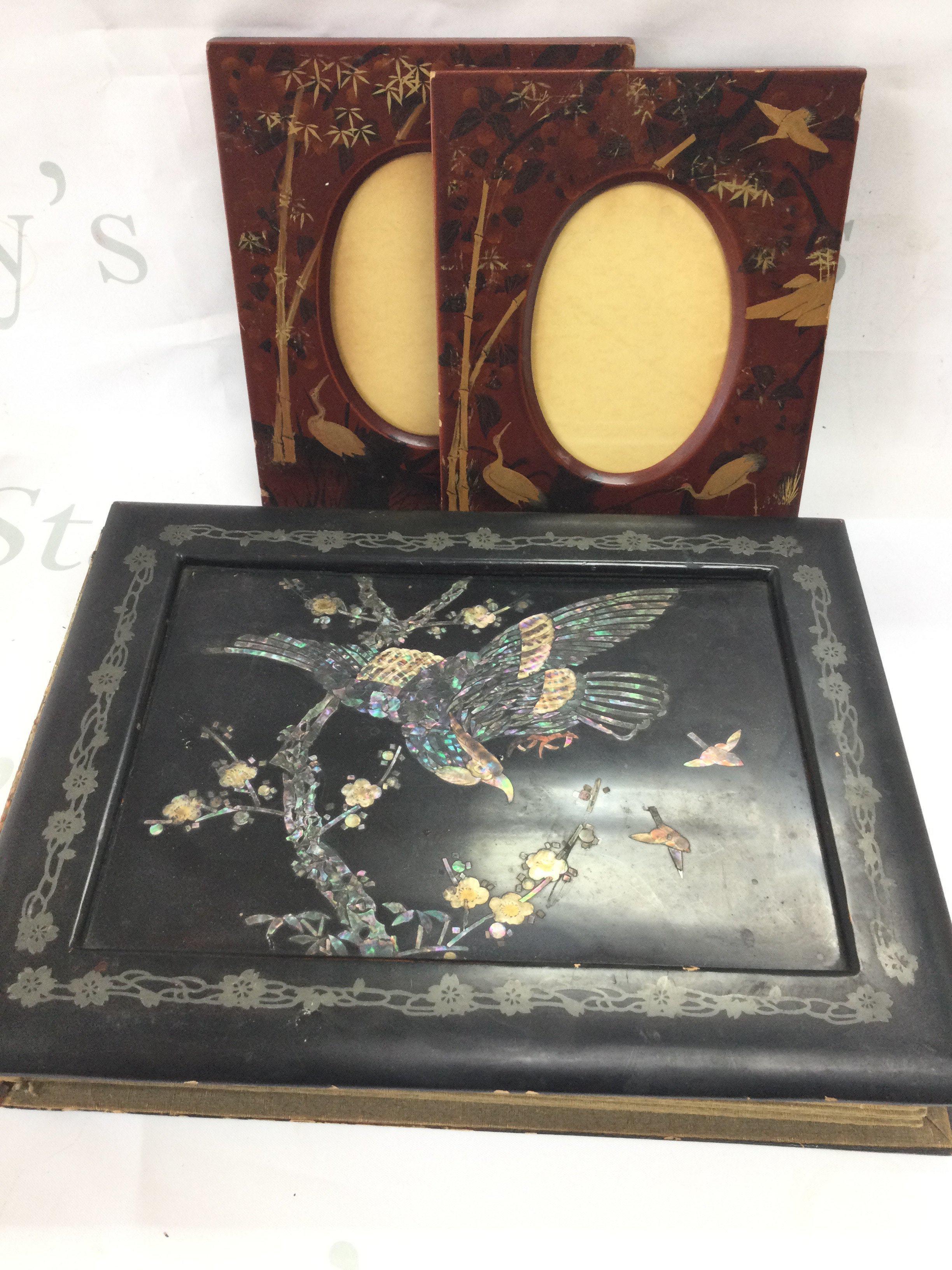 A Japanese lacquered album with silk paintings and a pair of Japanese oval photo frames with heron and bamboo decoration. Postage category C