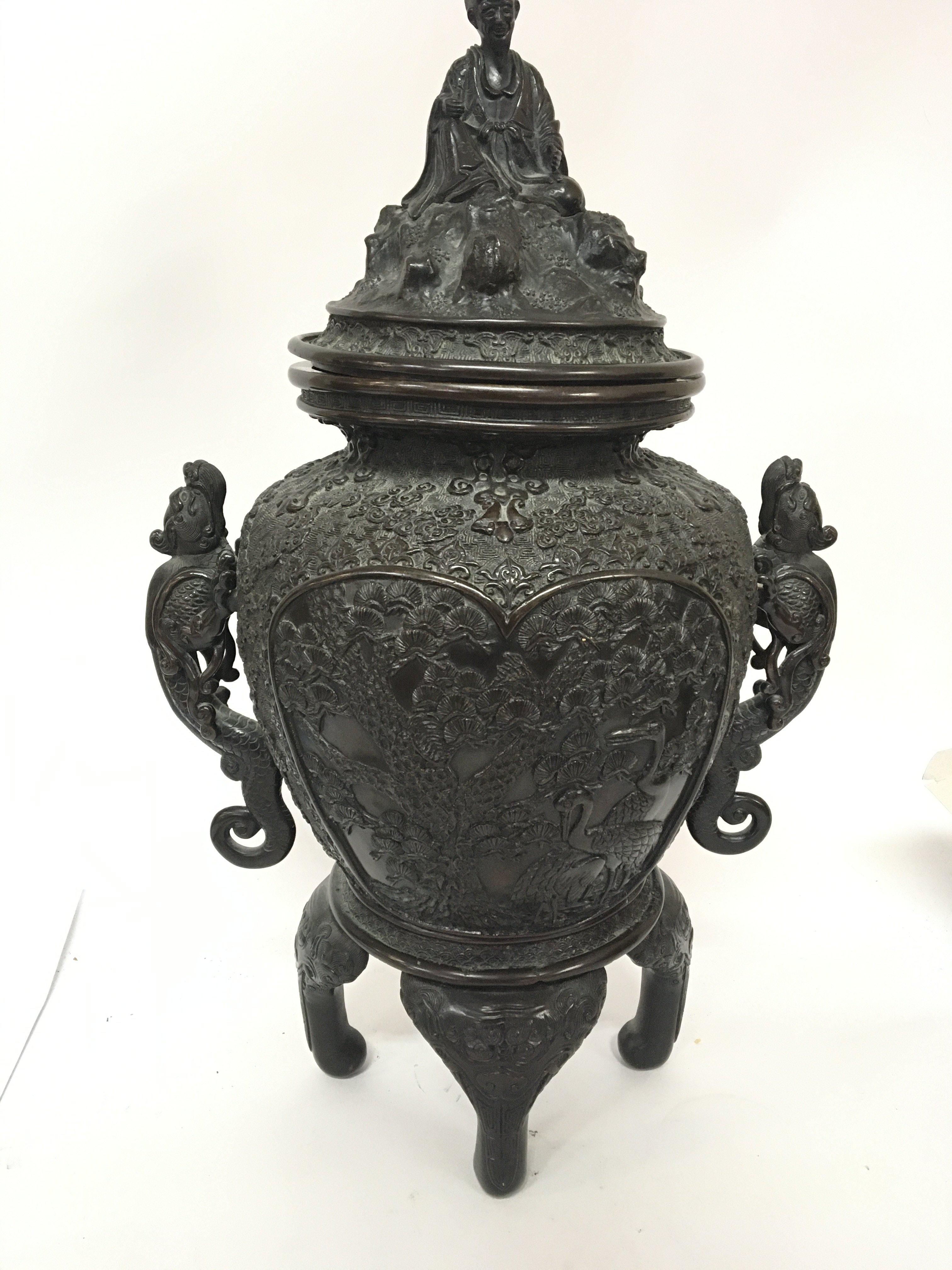 A large Chinese 19th century bronze vessel the cover in the form of a seated elder the profusely decorated sides with raised dragons on four shaped feet (one foot detached cover edge slightly miss shape. No obvious caricature marks. Height 55cm