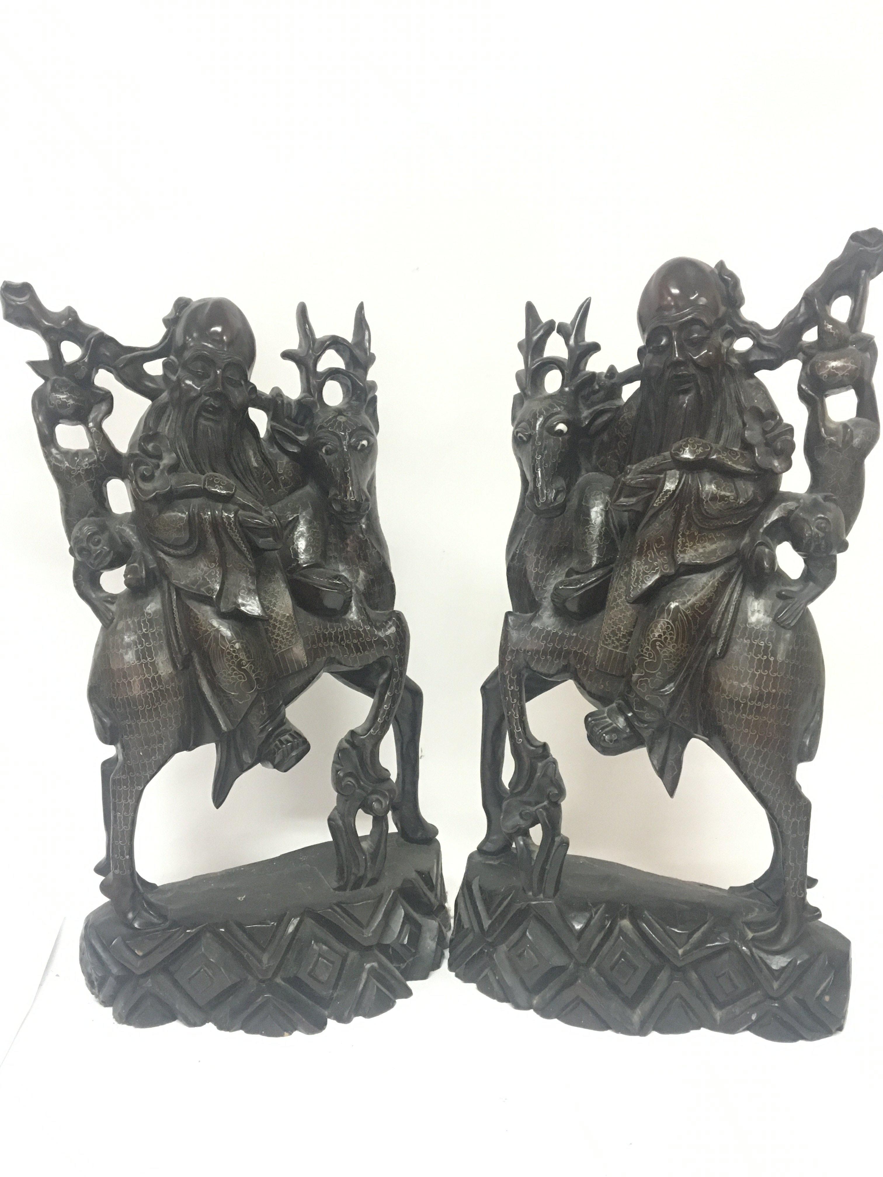 A pair of quality Chinese late 19th century carved hardwood figures in the form of elders seated on deer with hanging monkeys and delicately decorated with fine silver inlay Hight 46cm. Slight damage see illustrations.