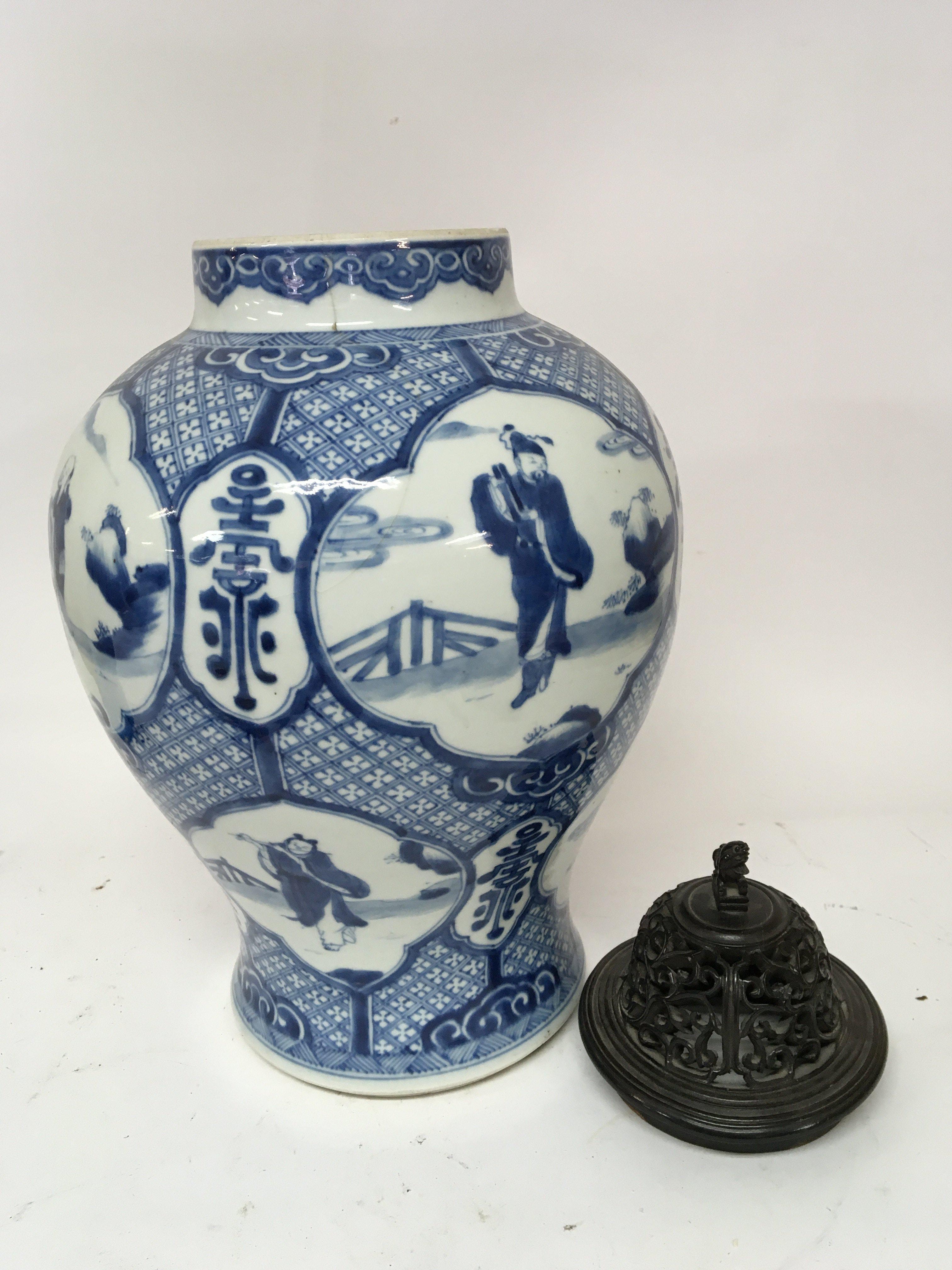 A Chinese Export porcelain blue and white 19th century vase decorated with panels of figures and of bulbs shape sold with a carved hardwood cover hairline crack hight 35cm.