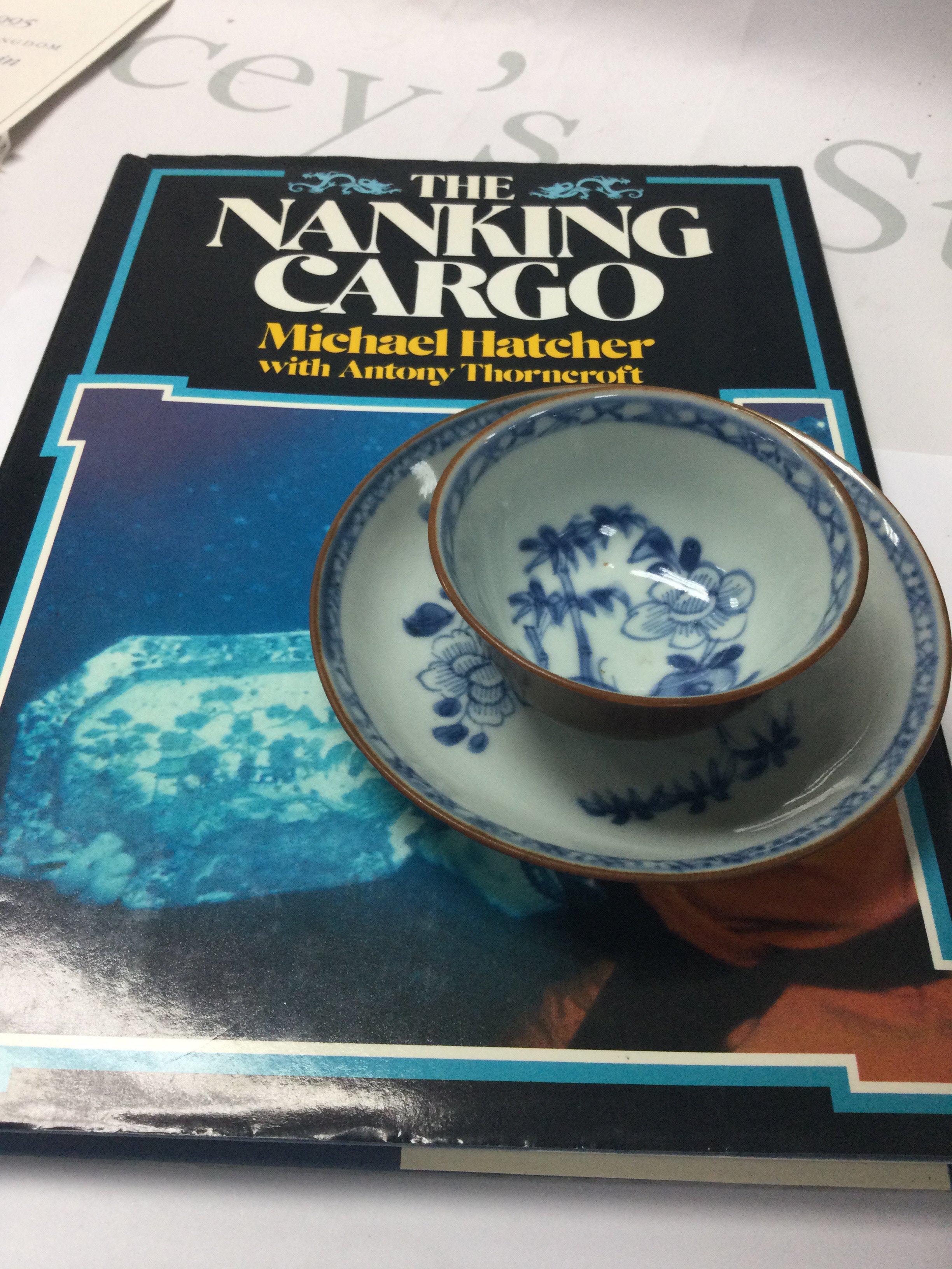 A Nanking Cargo tea bowl and saucer. Together with the book by Michael Hatcher .