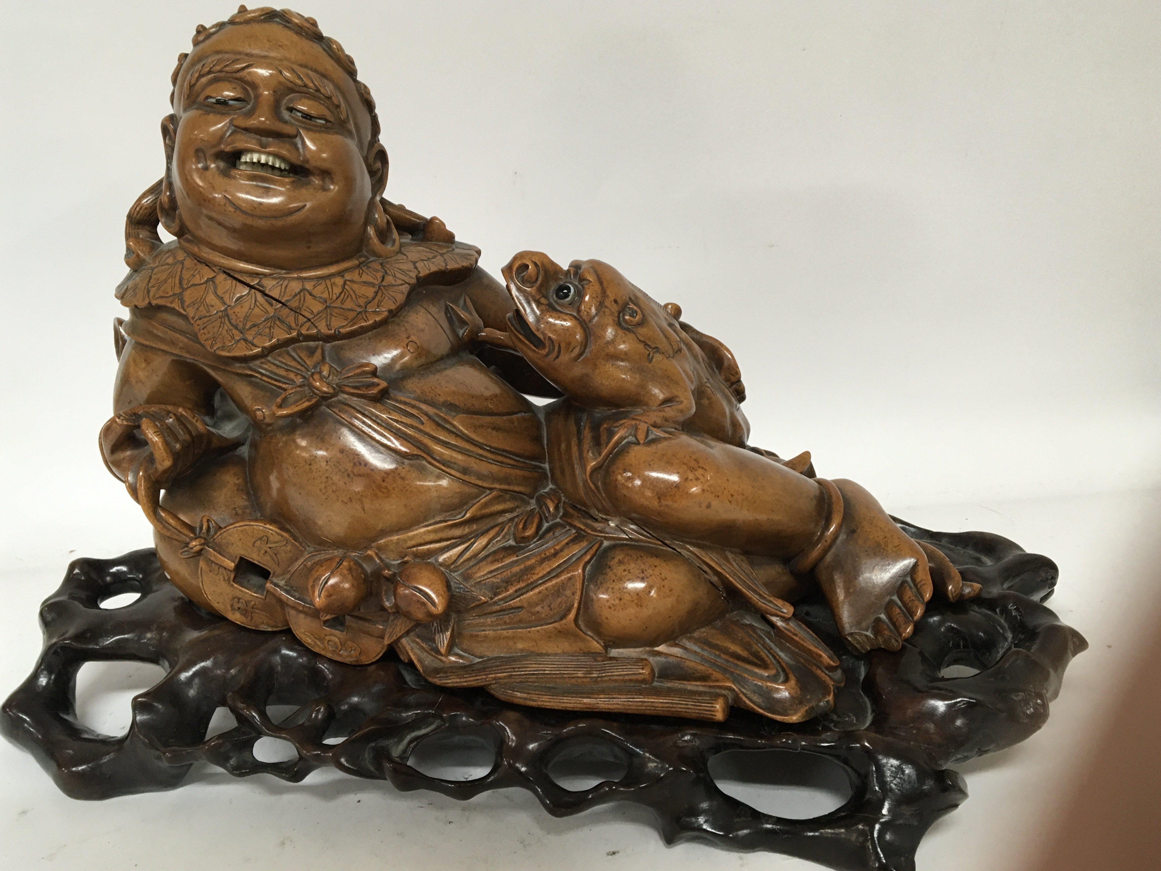 A late 19th century Chinese hardwood carving of a recycling figure with a comical toad on a contrasting carved hardwood base length 45cm.