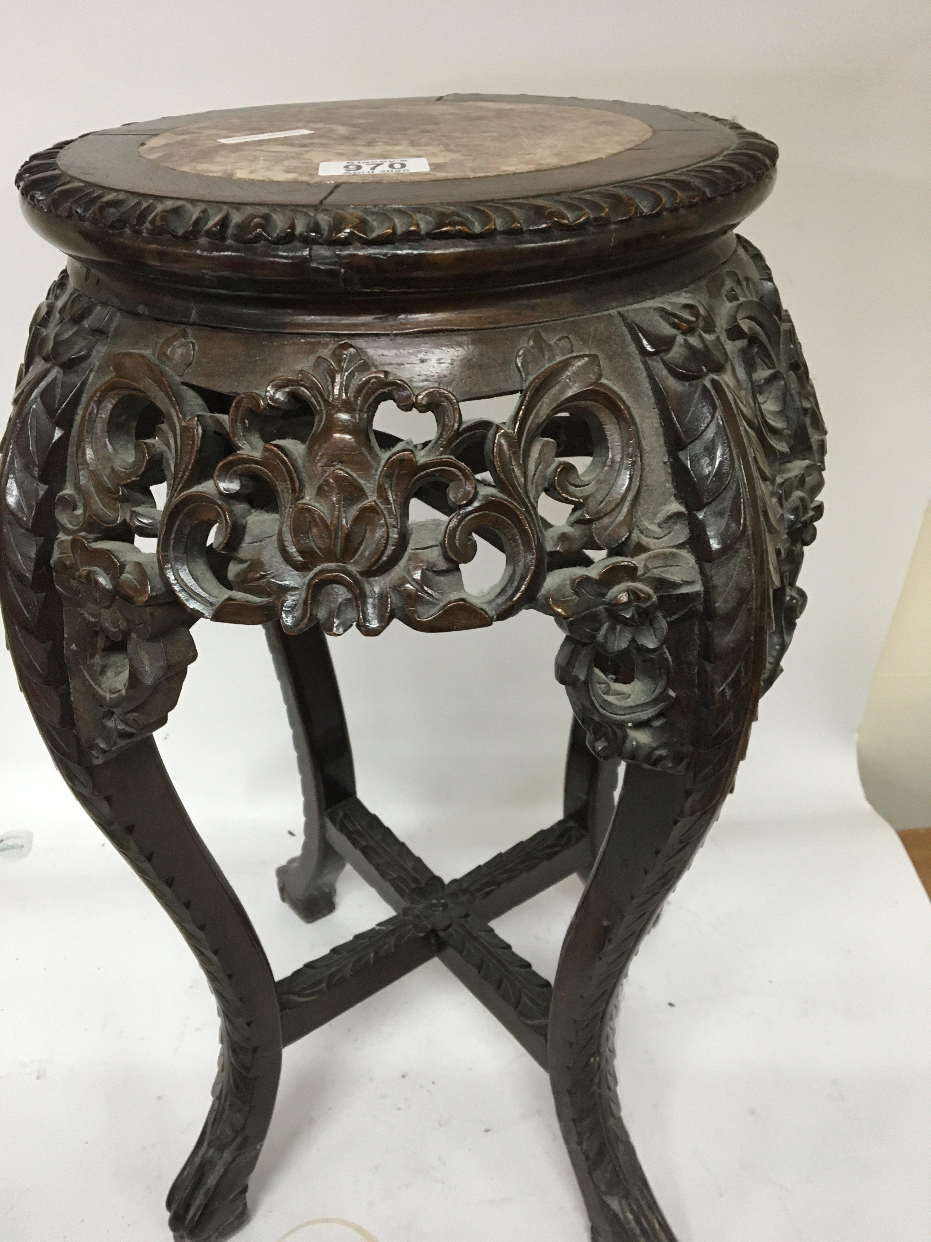 A Chinese carved hardwood jardiniere stand the round top inset with marble with a carved apron and legs United by stretchers. Height 61cm