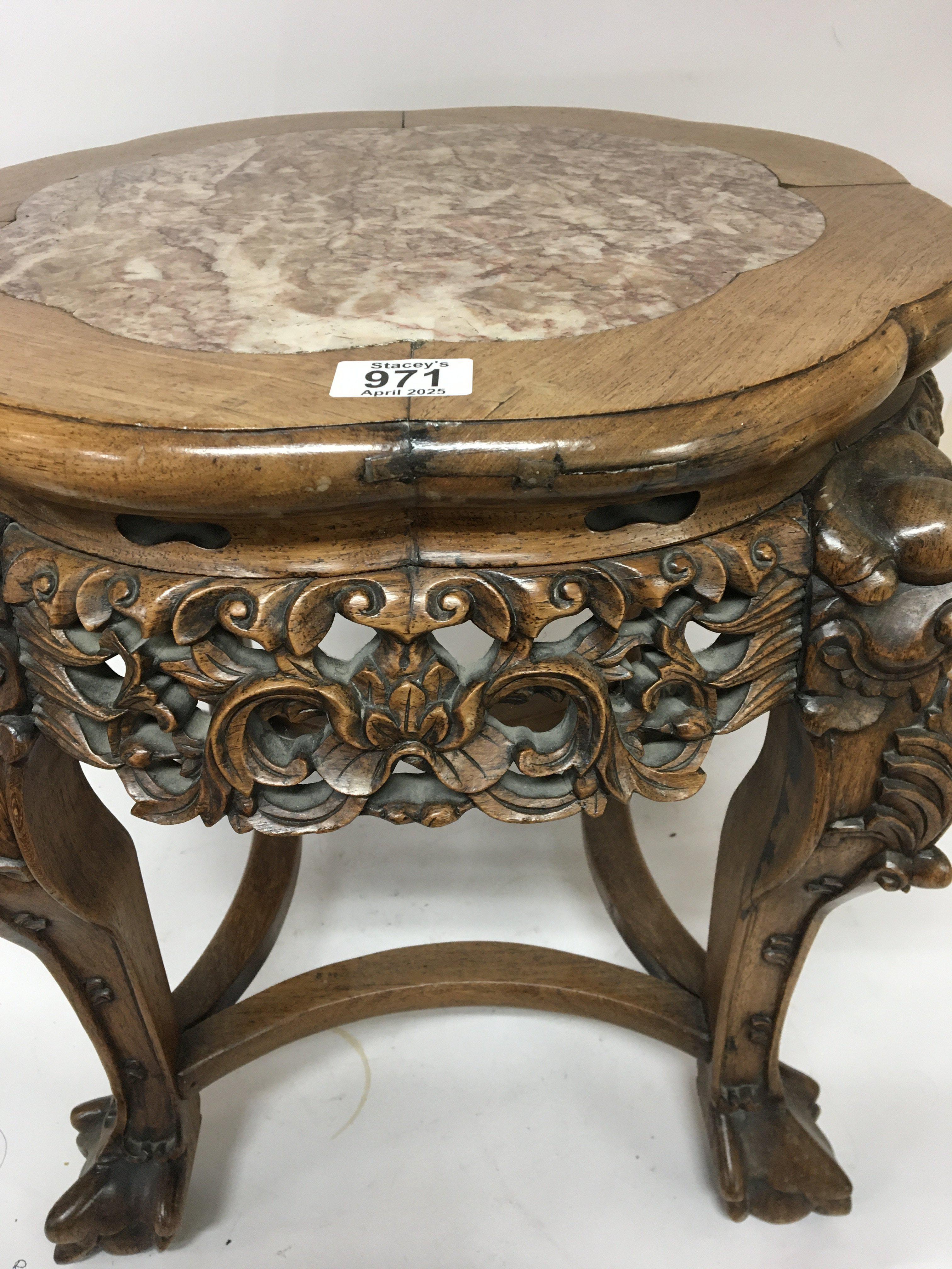 A Quality Chinese hardwood jardiniere stand with a shaped top inset with marble carved apron the legs with raised masks and ball and claw feet. Height 46cm.