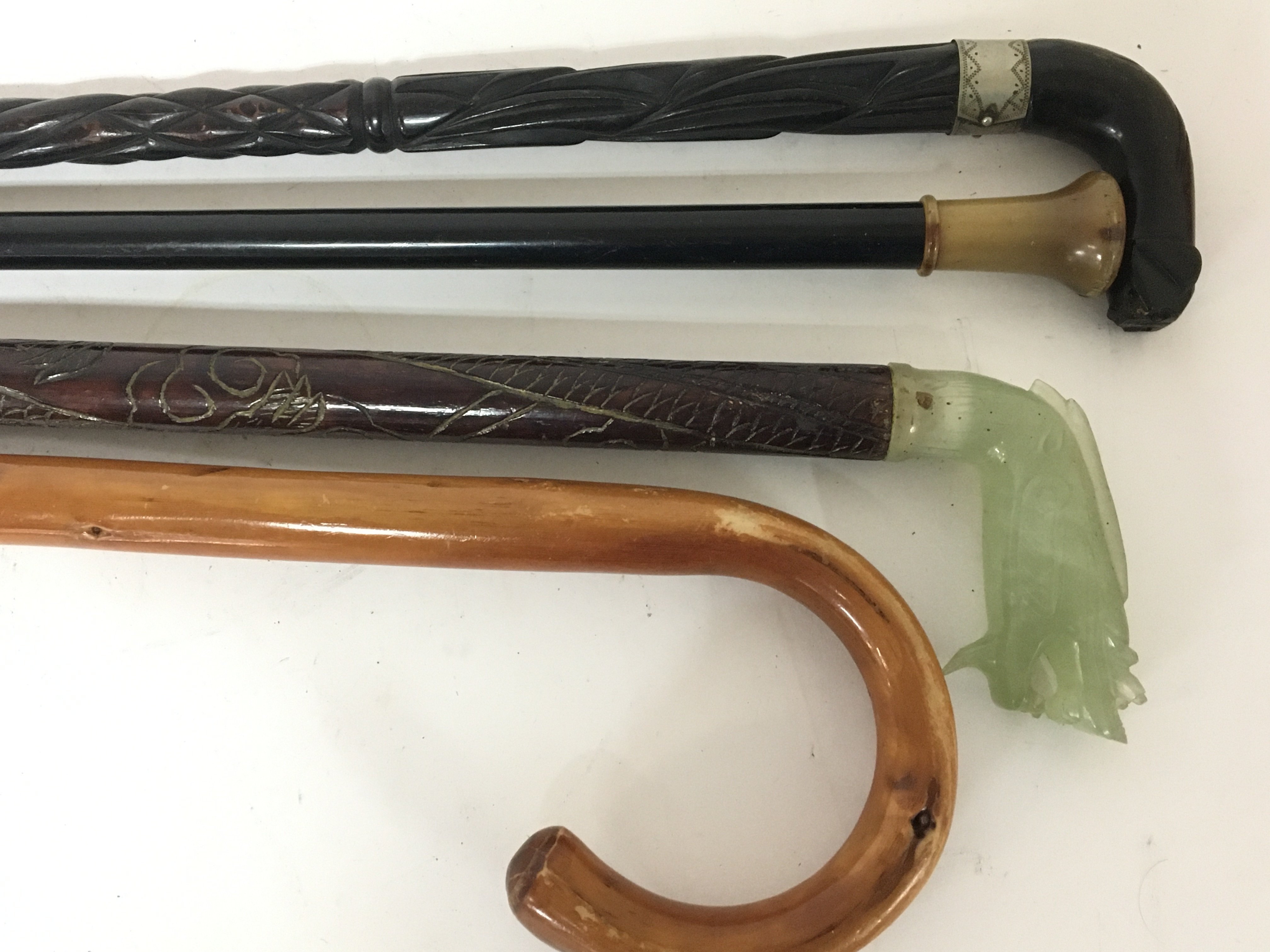 A Chinese walking stick with carved jade top in the form of a stylised dragon and three other walking sticks (4)