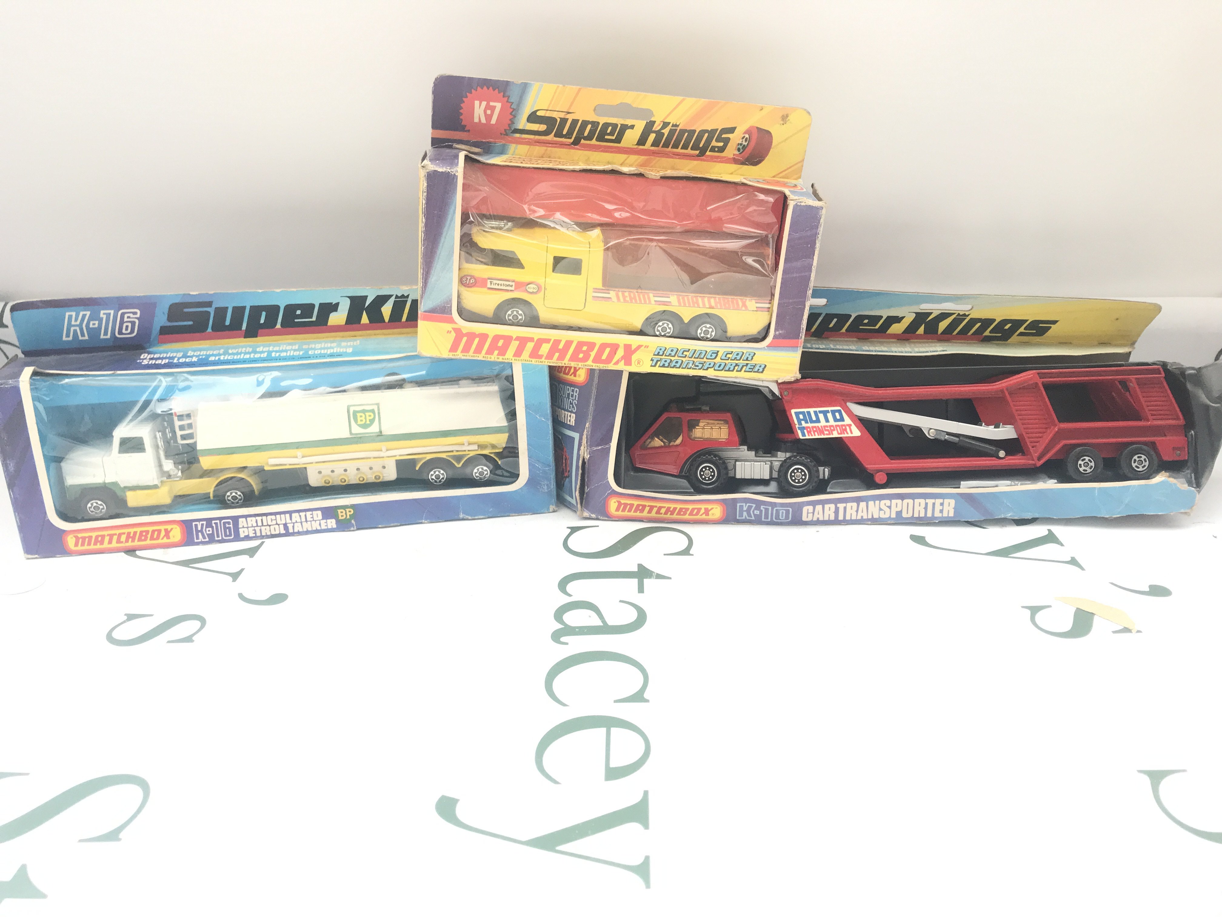 3 Boxed Matchbox Vehicles. Boxes In Various States. A Articulated Petrol Tanker #K-16. A Racing Car Transporter #K-7 And A Car Transporter #K-10.
