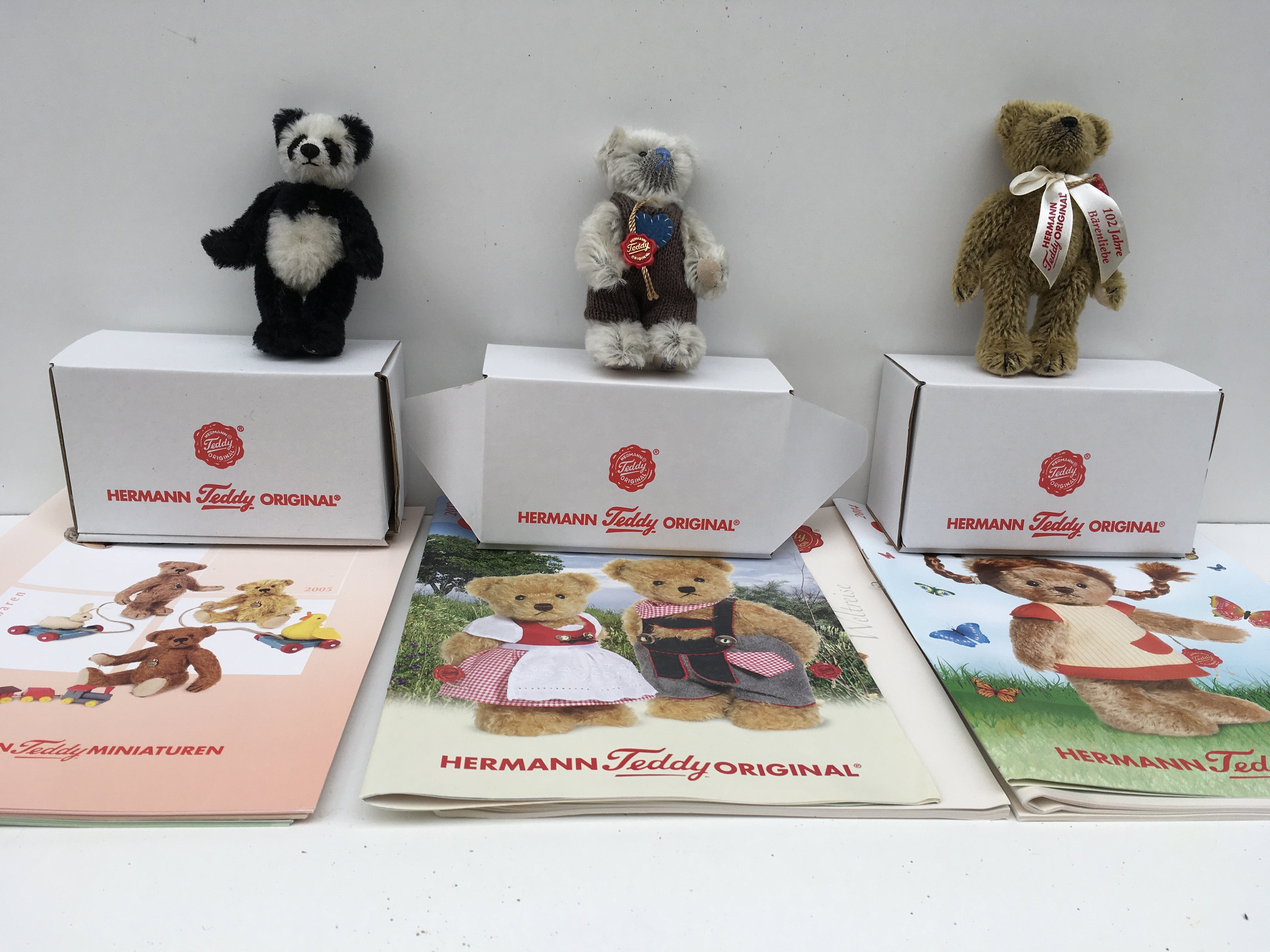 Three boxed Herman minature teddies featuring a Panda bear from 2005 a light grey bear from 2012 and a golden brown bear from 2014. Includes associated magazines. No reserve