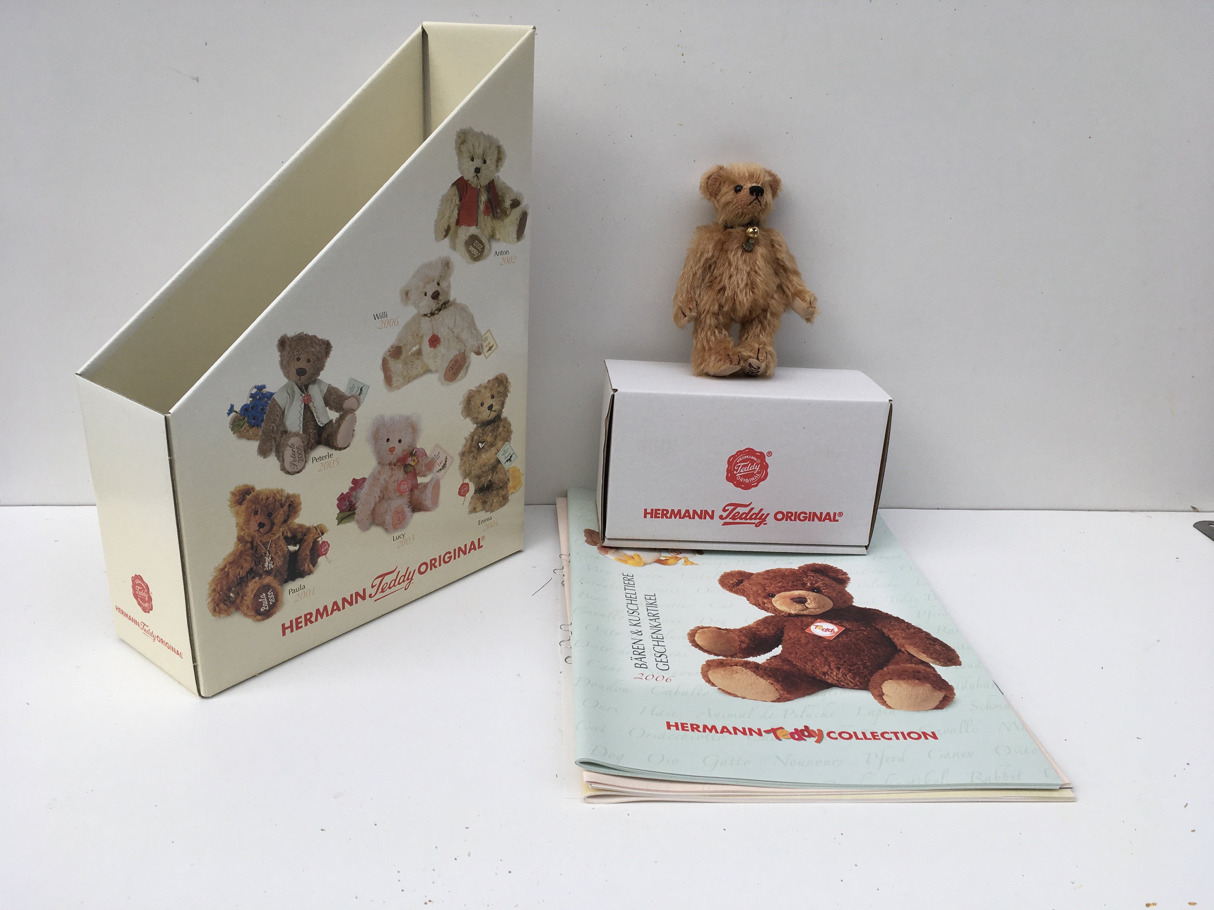A boxed Herman minature 12 cms brown teddy bear from 2006 with bell on collar. Also includes magazines and storage holder. No reserve