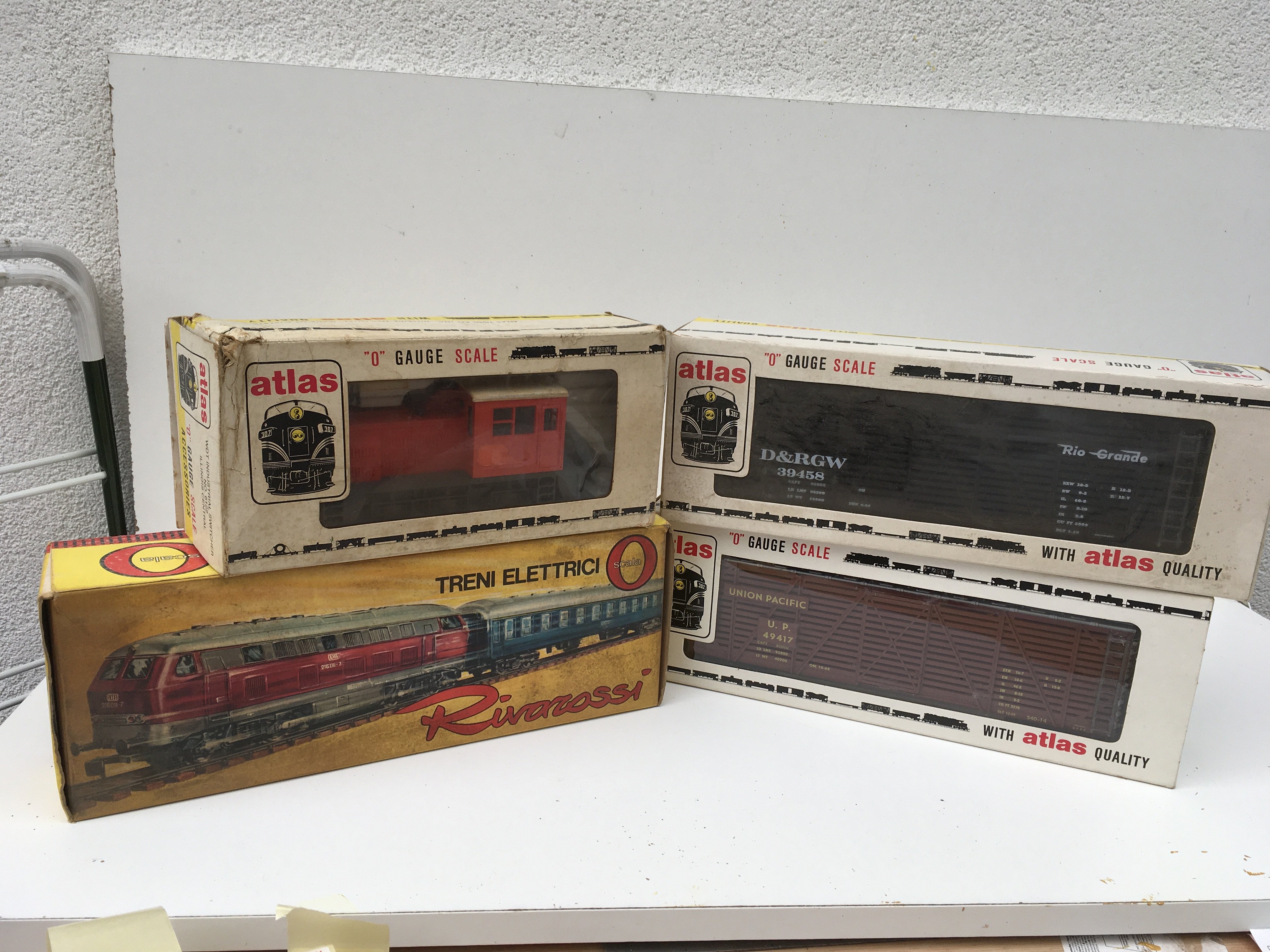 2x Boxed 0 gauge locomotives by Atlas and Rivarossi and 2x 40ft Stock Cars by Atlas. Features a shunting diesel Santa Fe and WDT Industrial Switcher. No reserve