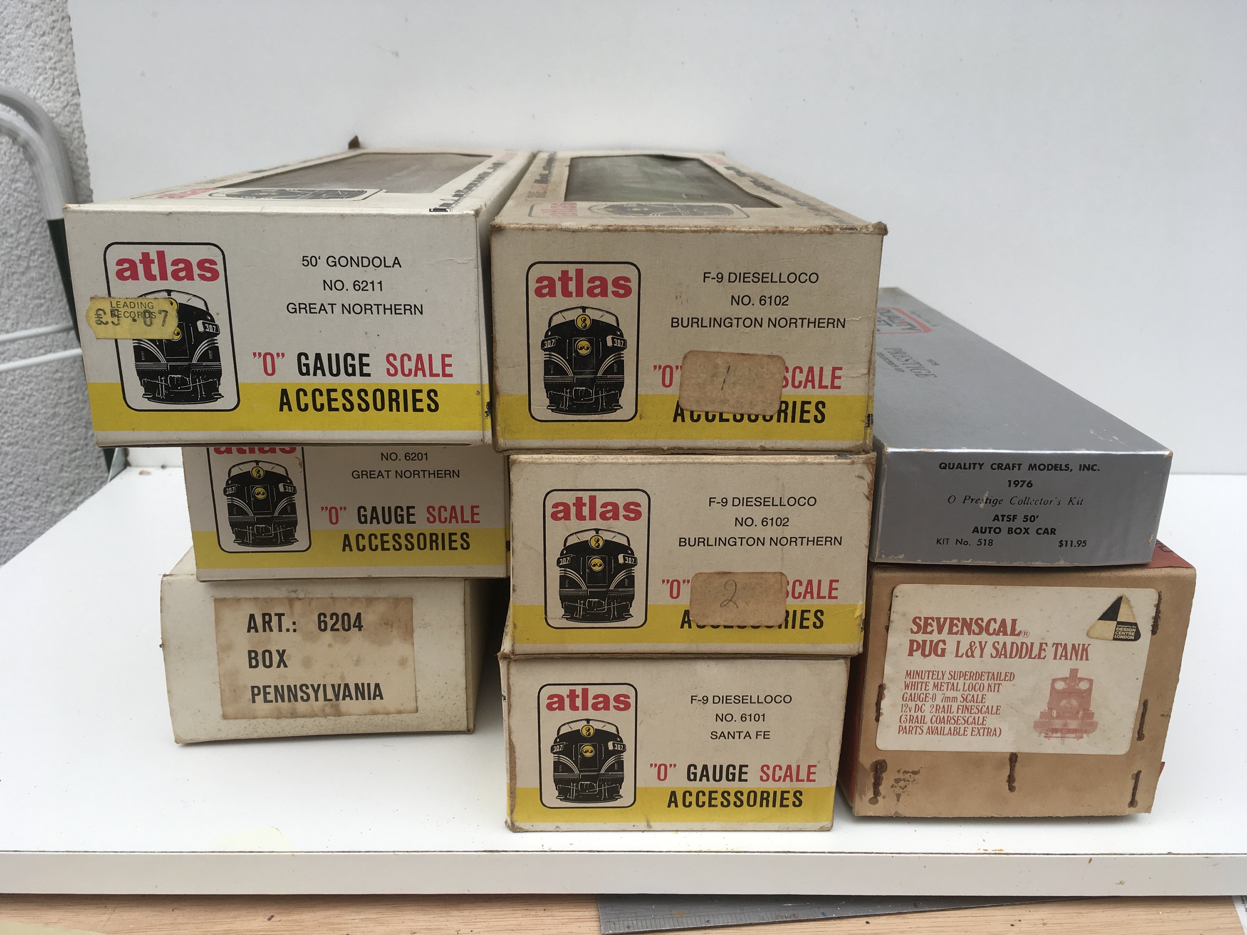 A collect of 8x boxed O gauge model railway pieces including 3 diesel locomotives by Atlas..A Sevenscal Pug loco kit. Plus 3 boxed wagons and Quality Craft Model kit of 50ft box car. No reserve