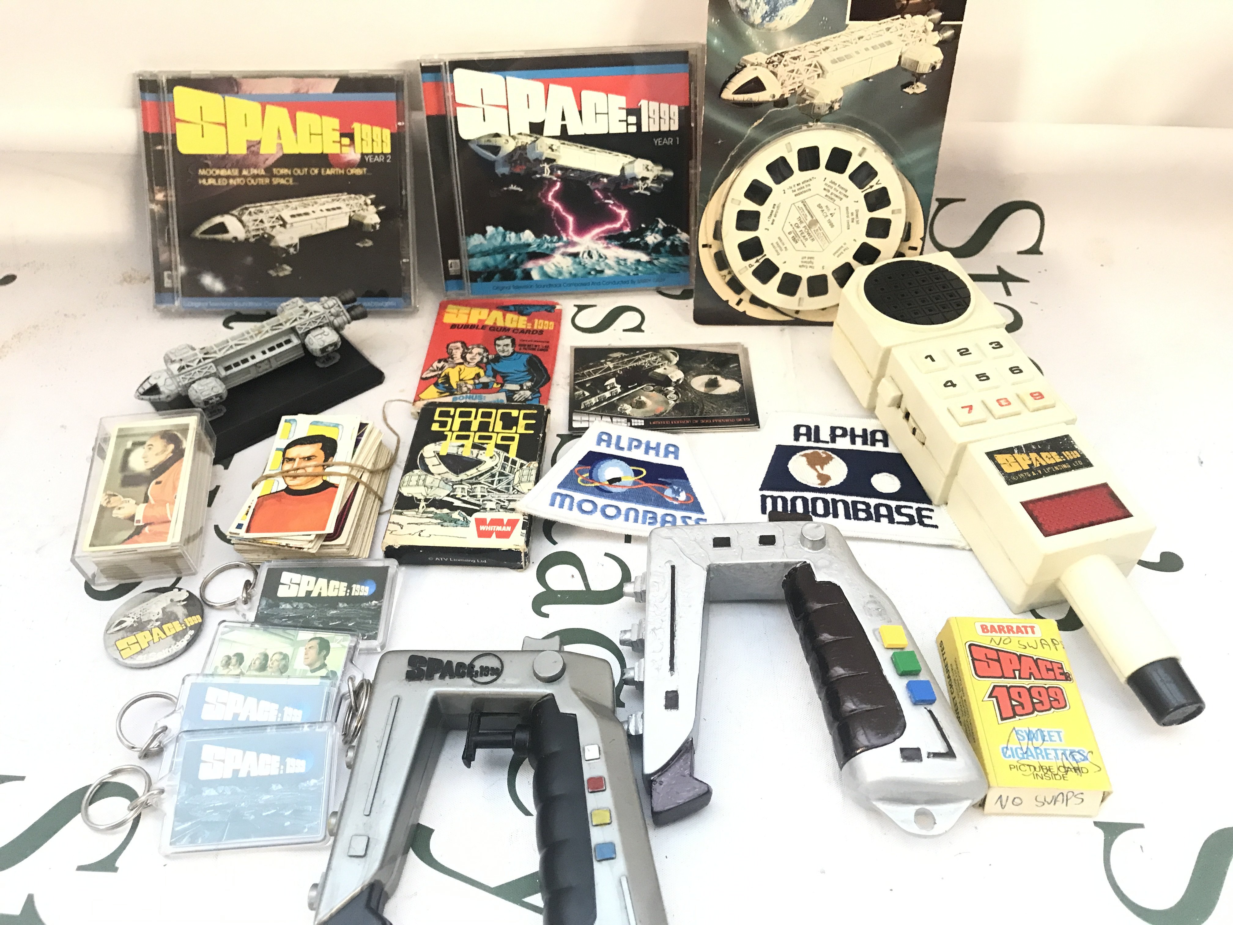 A Small Collection Of Space 1999 Toys Key Rings etc. including A Sealed Packet Of Bubble Gum Cards. No Reserve.