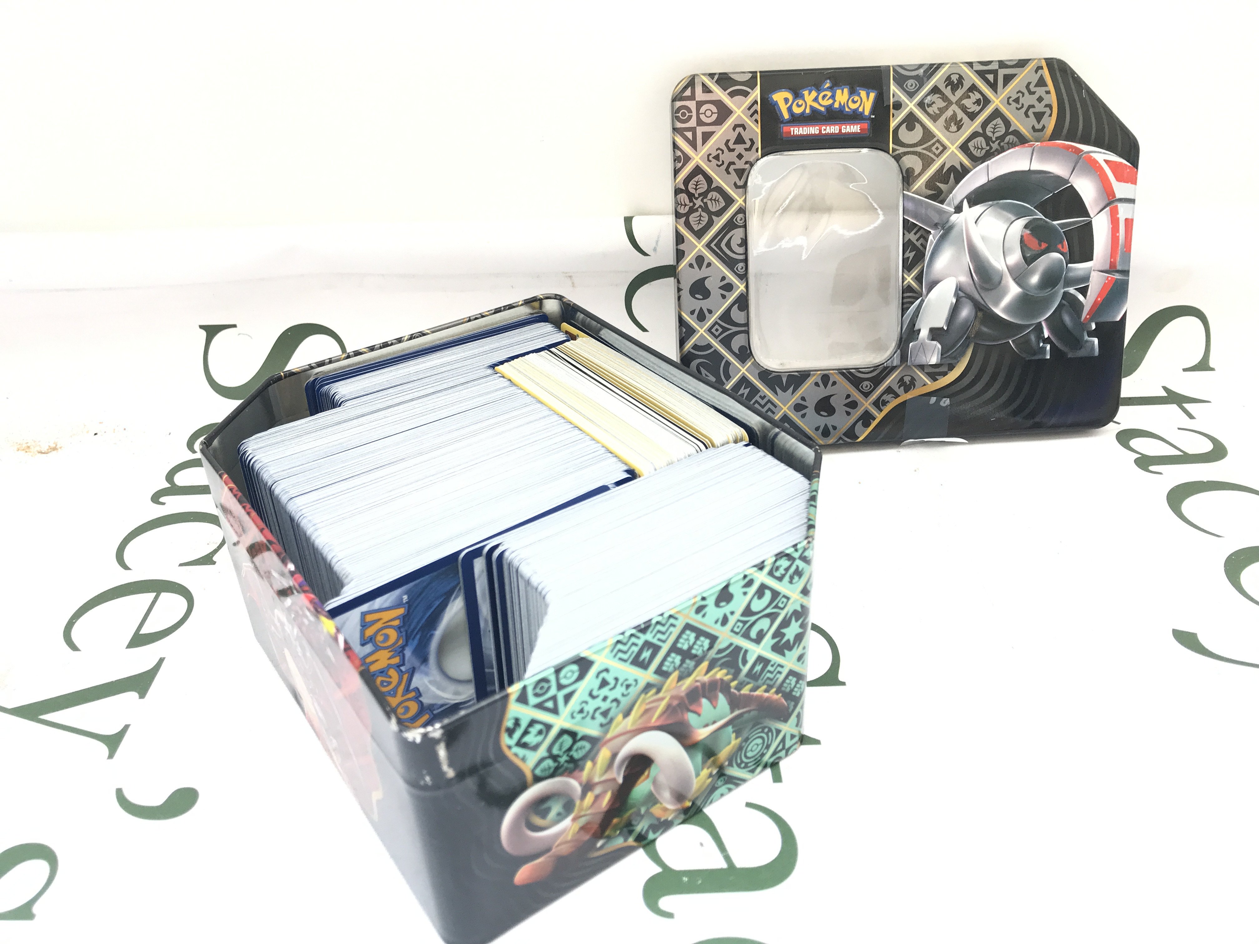 A Collection of 600+ modern Pokemon Cards Including Holographic And Japanese Holos. In Pokemon Tin.