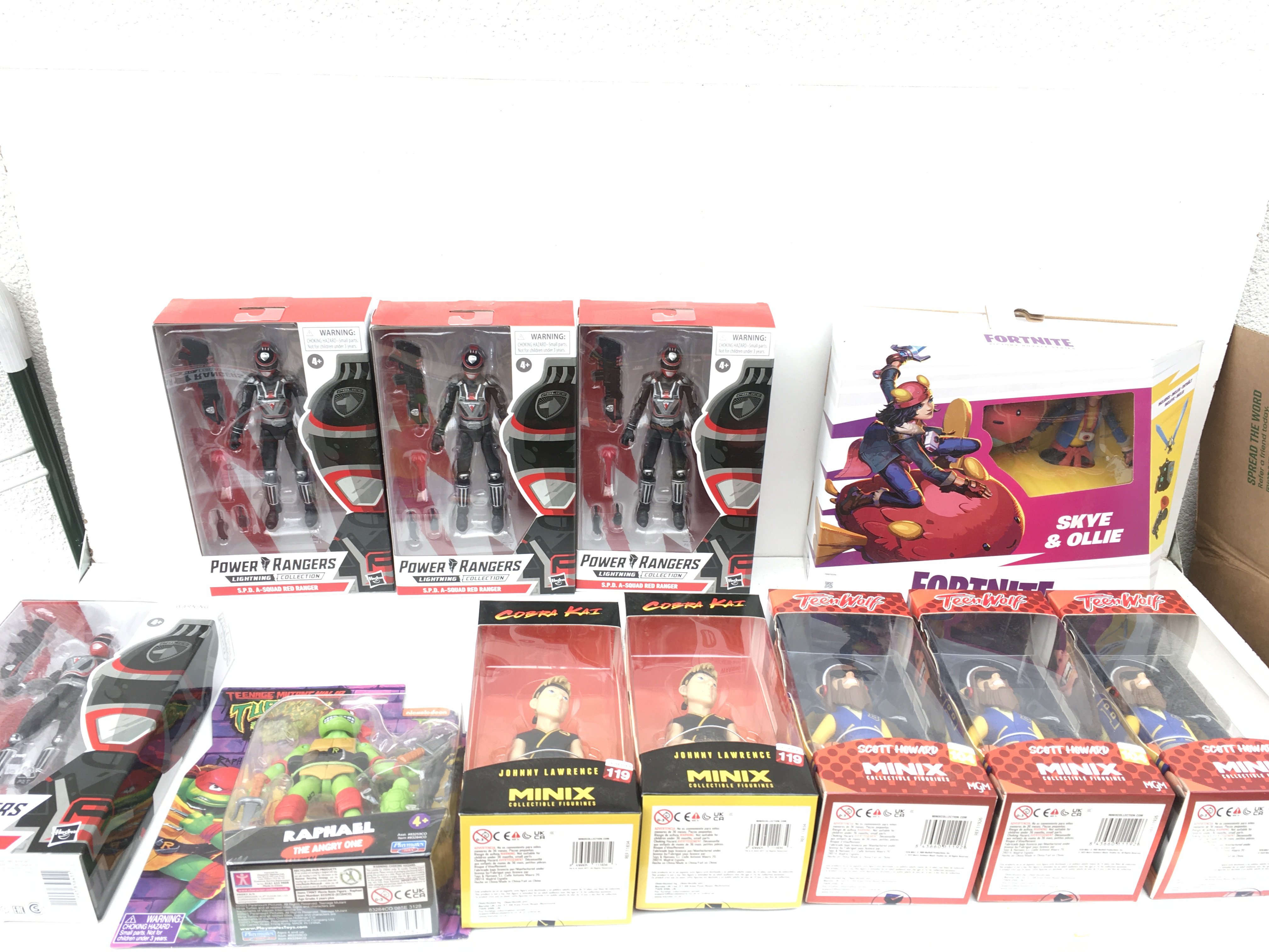 A collection of 11 boxed and unopened action figures featuring Hasbro Power Rangers from the Lightening Collection.. Teenage Mutant Ninja Turtle. Raphael by Playmates..Johnny Lawrence Cobra Kai by Minix..Scott Howard Teen Wolf by Minix and Skye and Ollie Fortnite victory royals series by Hasbro.