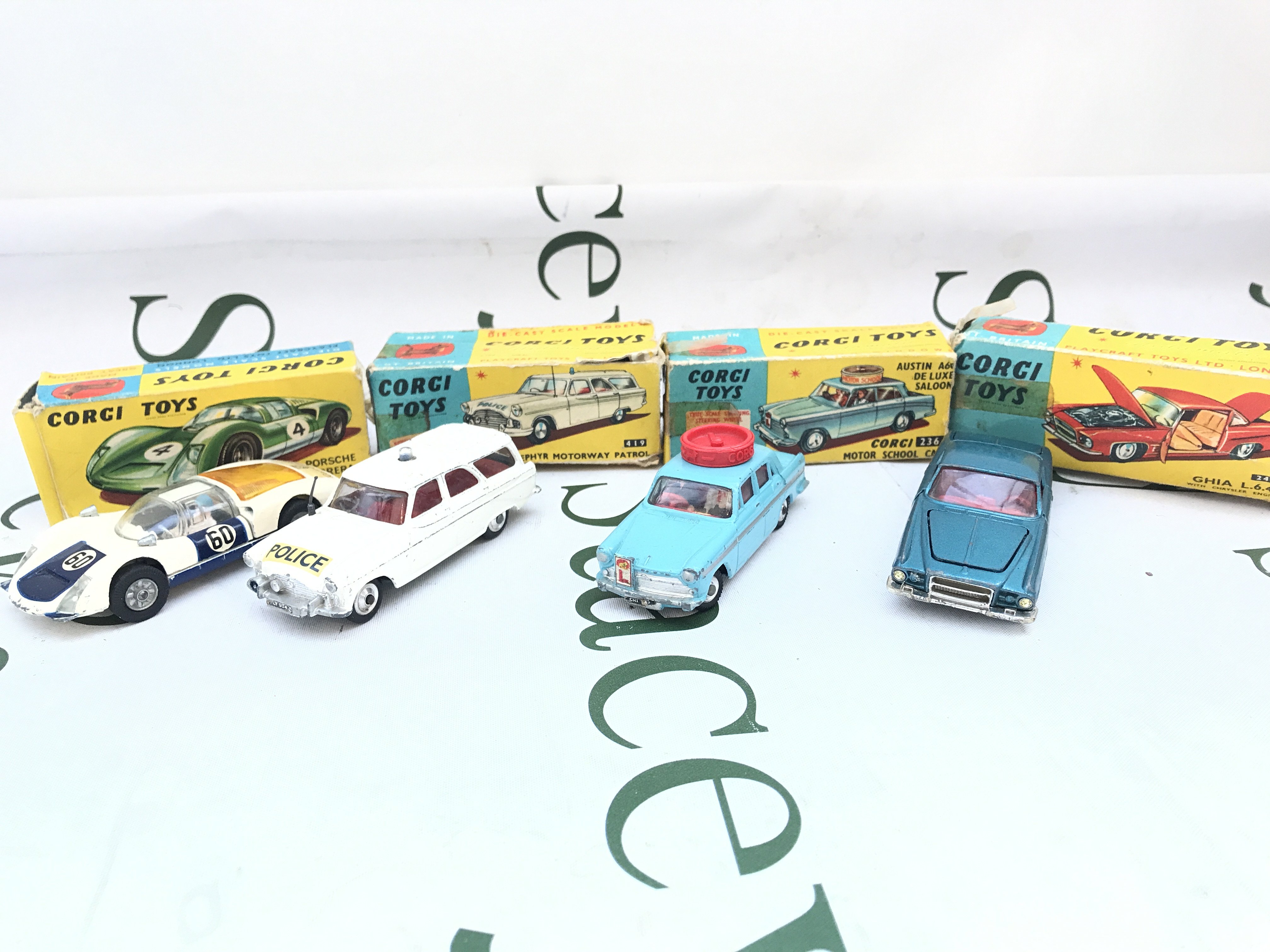 4 Boxed Corgi Vehicles. A Porsche Carrera 6 #330. A Ford Zephyr #419. A Motor School Car #236 And A Ghia L.6.4 #241. Boxes Are Worn.