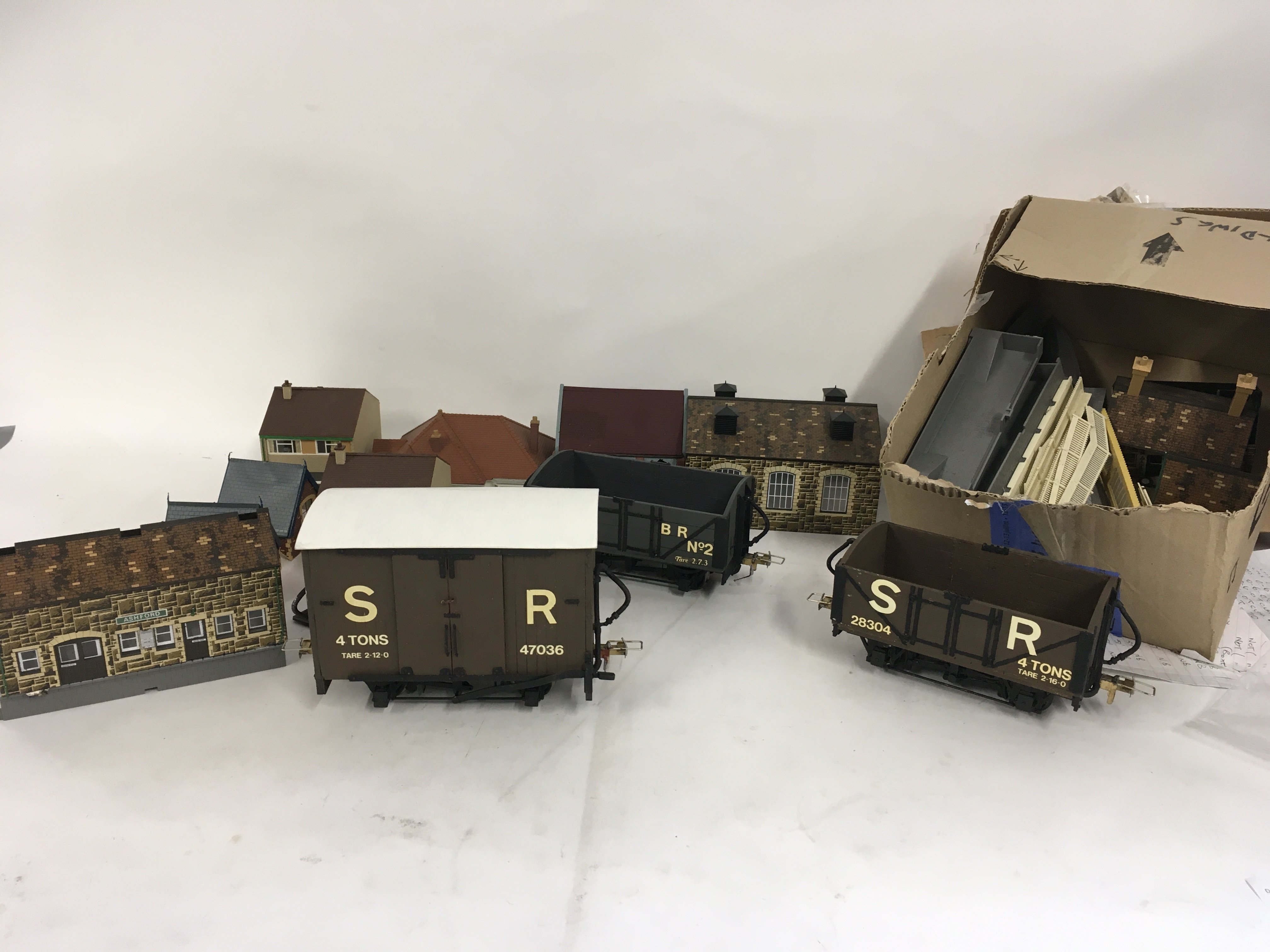 A selection of plastic model buildings for a railway or village scene some assembled. Also 3 x 0 gauge model railway wagons. No reserve
