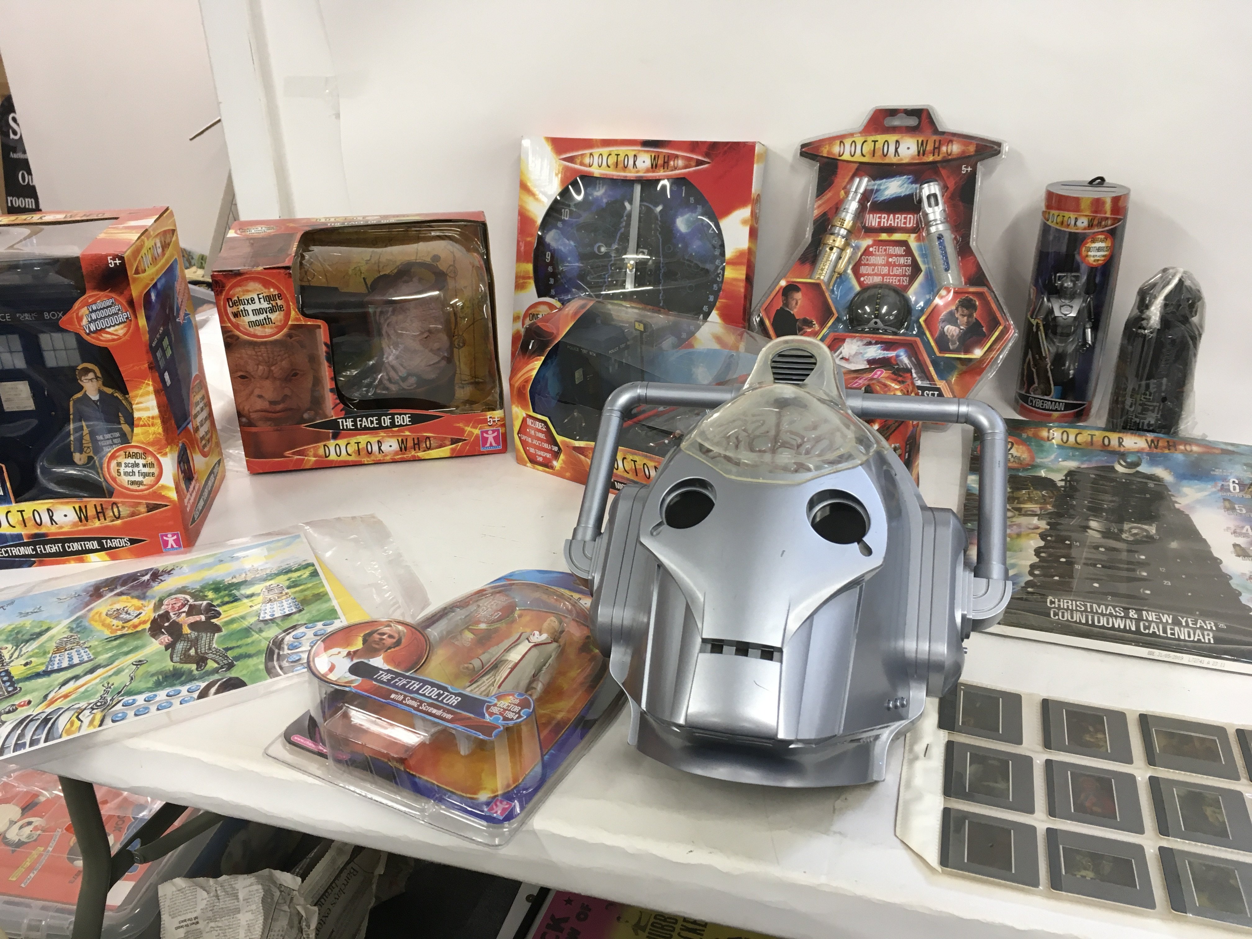 A collection of boxed Dr Who toys including Electronic Flight Control Tardis. The face of Boe with moveable mouth. Micro universe 3 spaceship set. The Firth Doctor. Dalek Wallclock. Sonic and Laser Screwdriver set. Cyber man with rotary toothbrush. Set of 12 viewing slides featuring first 8 doctors and others. Advent Calendar 2009. Waterbottle and a used cyberman electronic mask. Plus a limited print featuring the 1st Doctor and the Daleks signed by Walt Howarth with COA.