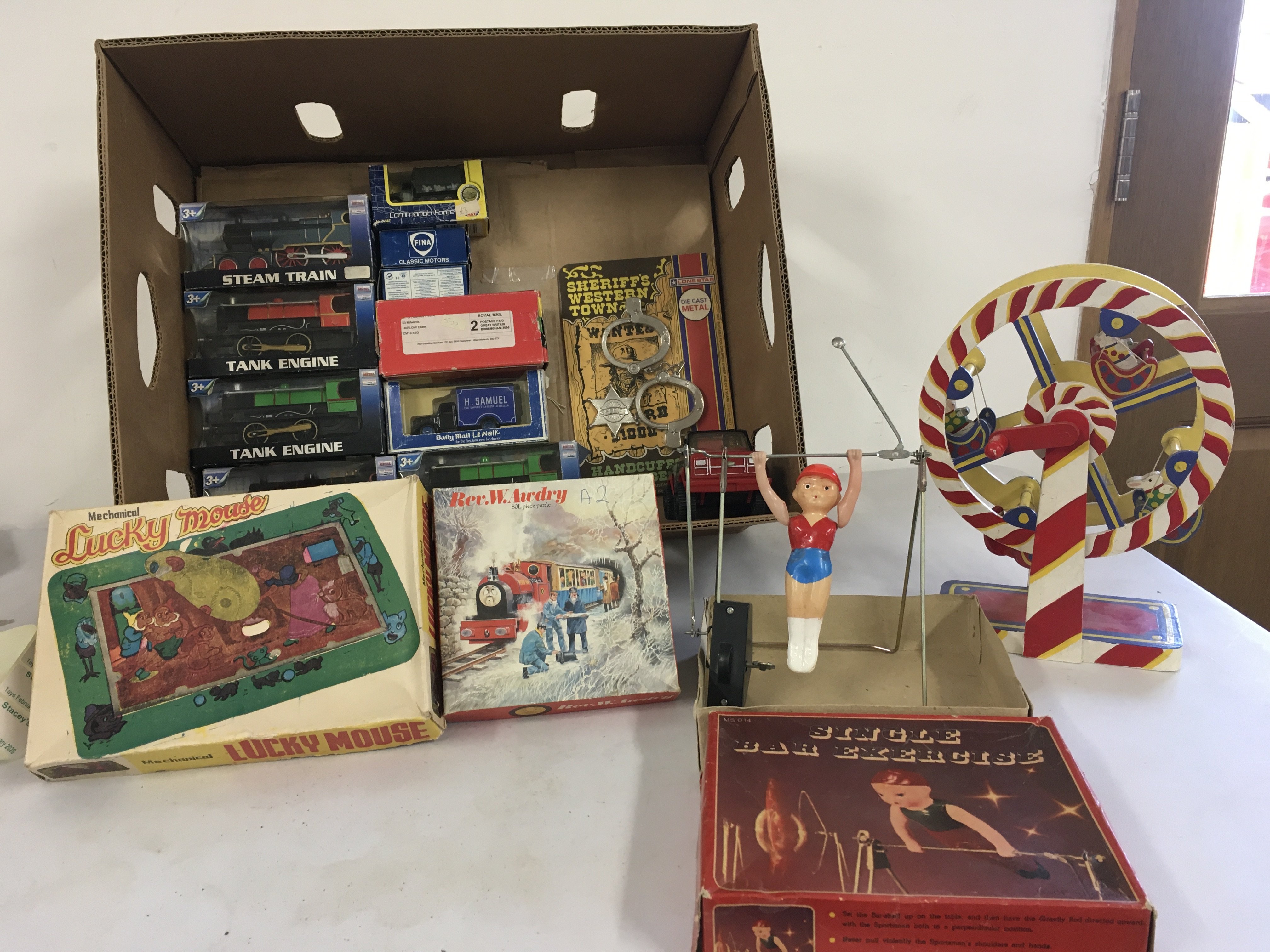 A mixed collection of toys with some vintage tin.   Includes Boxed mechanical clockwork  Lucky Mouse a boxed clockwork Single Bar Exercise. plus boxed locos ..jigsaw..cars hand operated ferris wheel etc.  no reserve. 