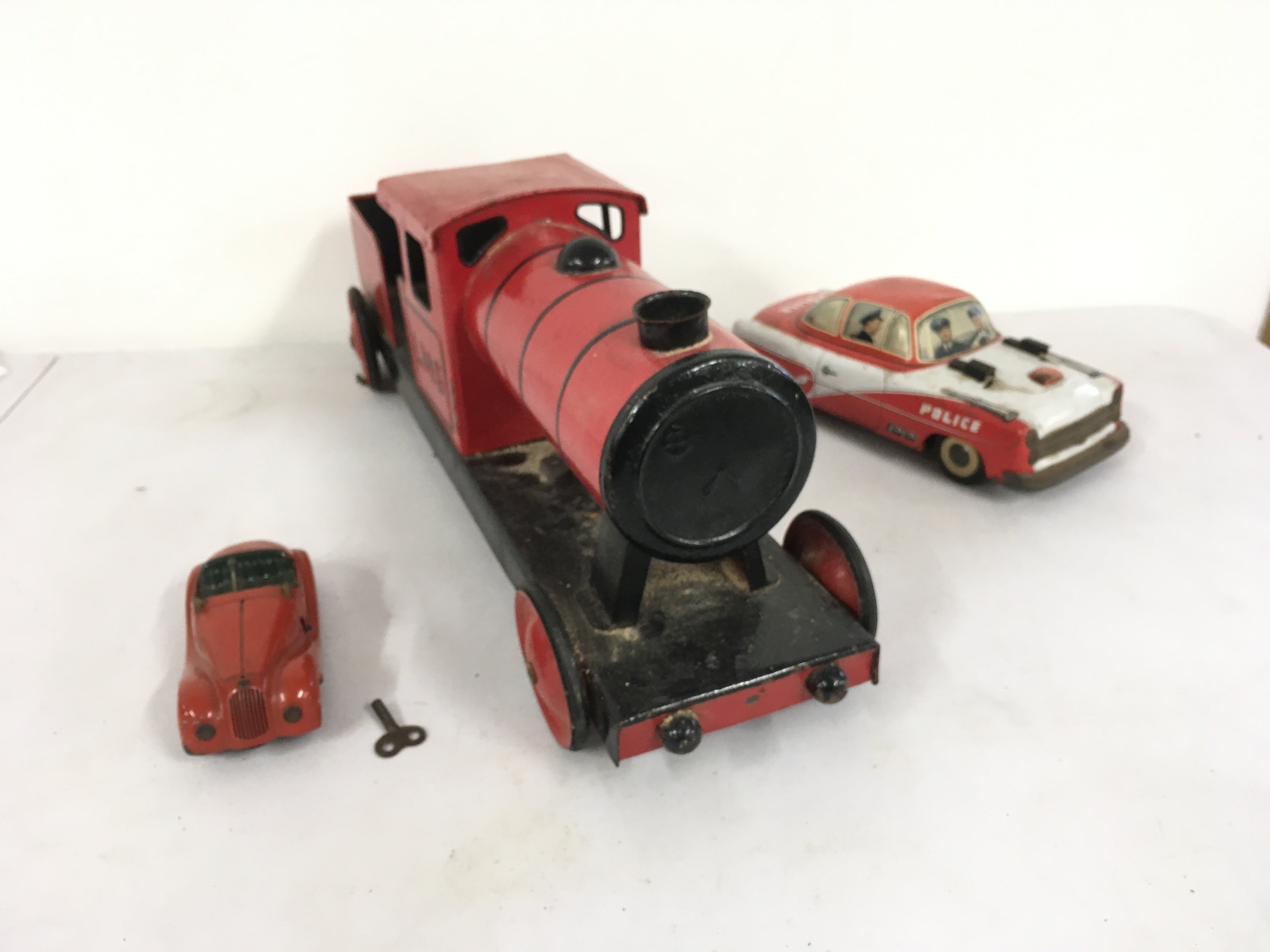 3x tin model vehicles including 1x Schuco Examico 4001 clockwork car with key.  A litho print friction model police car possibly Philipp lowmeier.   Also a locomotive with 4 wheels  unbranded.  No reserve 