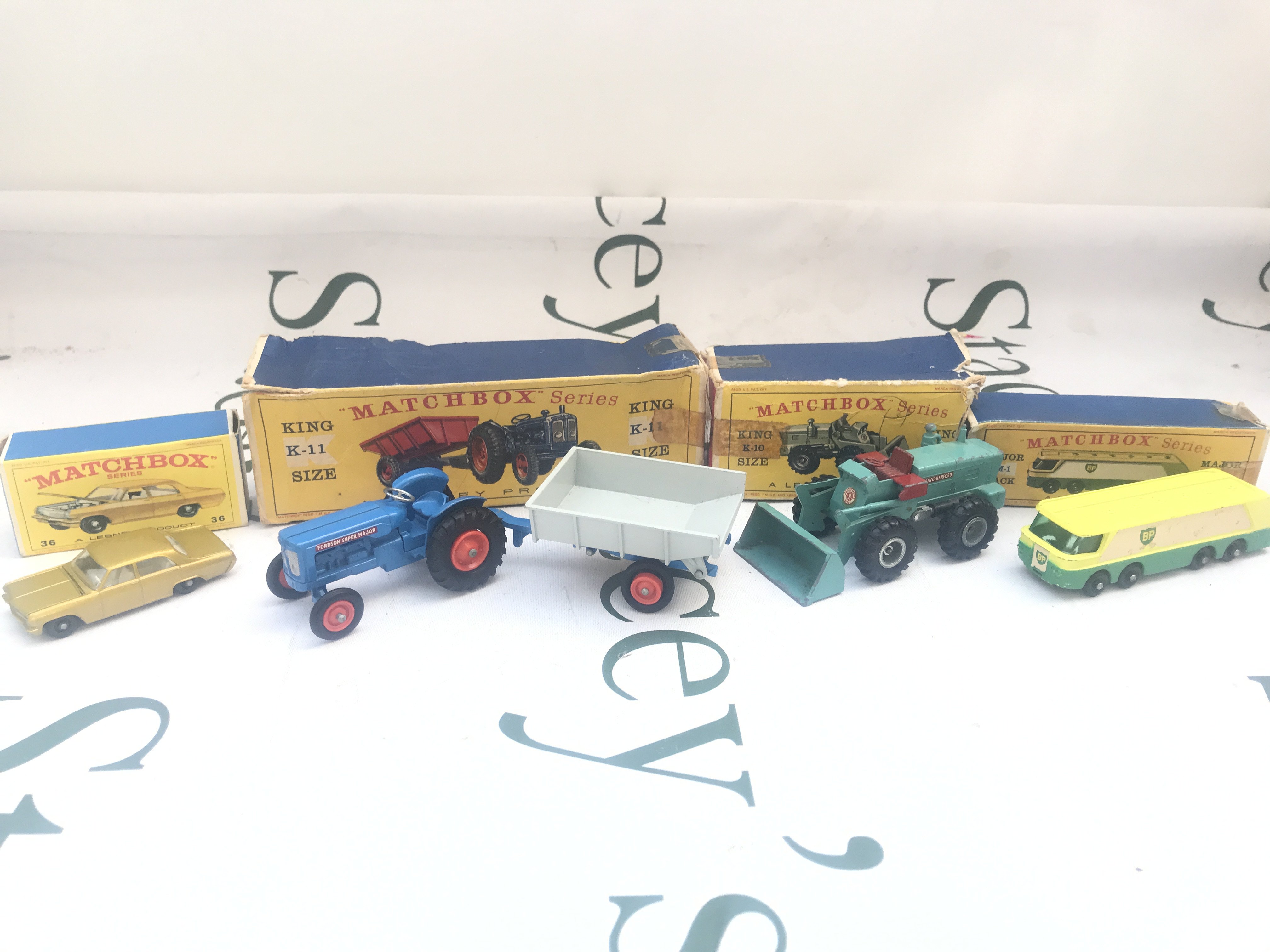A Collection Of 4 Matchbox Vehicles. A Opel Diplomat #36 A Fordson Tractor and Trailer K-11. A Tractor Shovel #K-10 And A BP Petrol Tanker #M-1. Boxes Are Worn.
