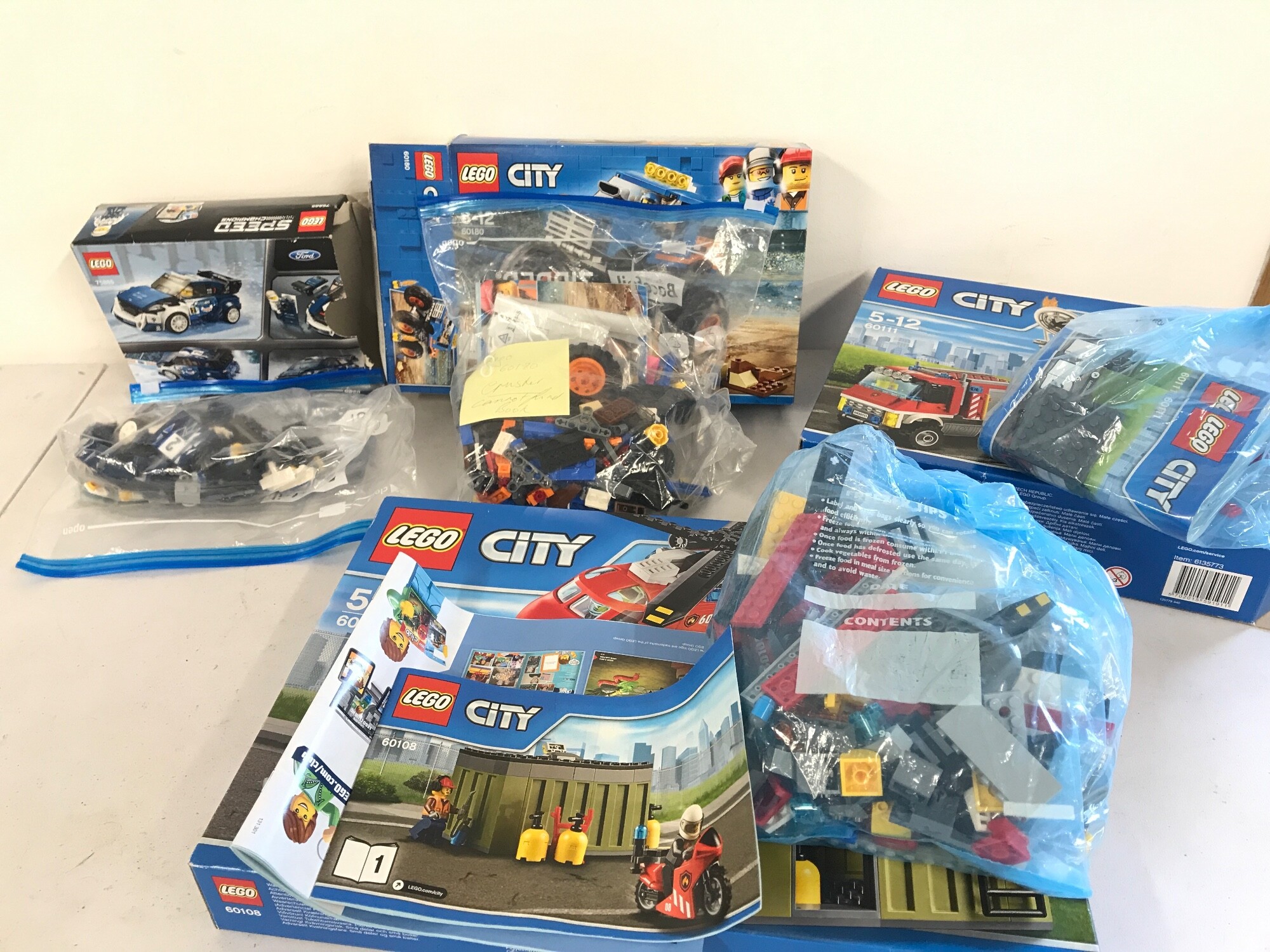 Three open Lego city sets and a Lego speed champion set.