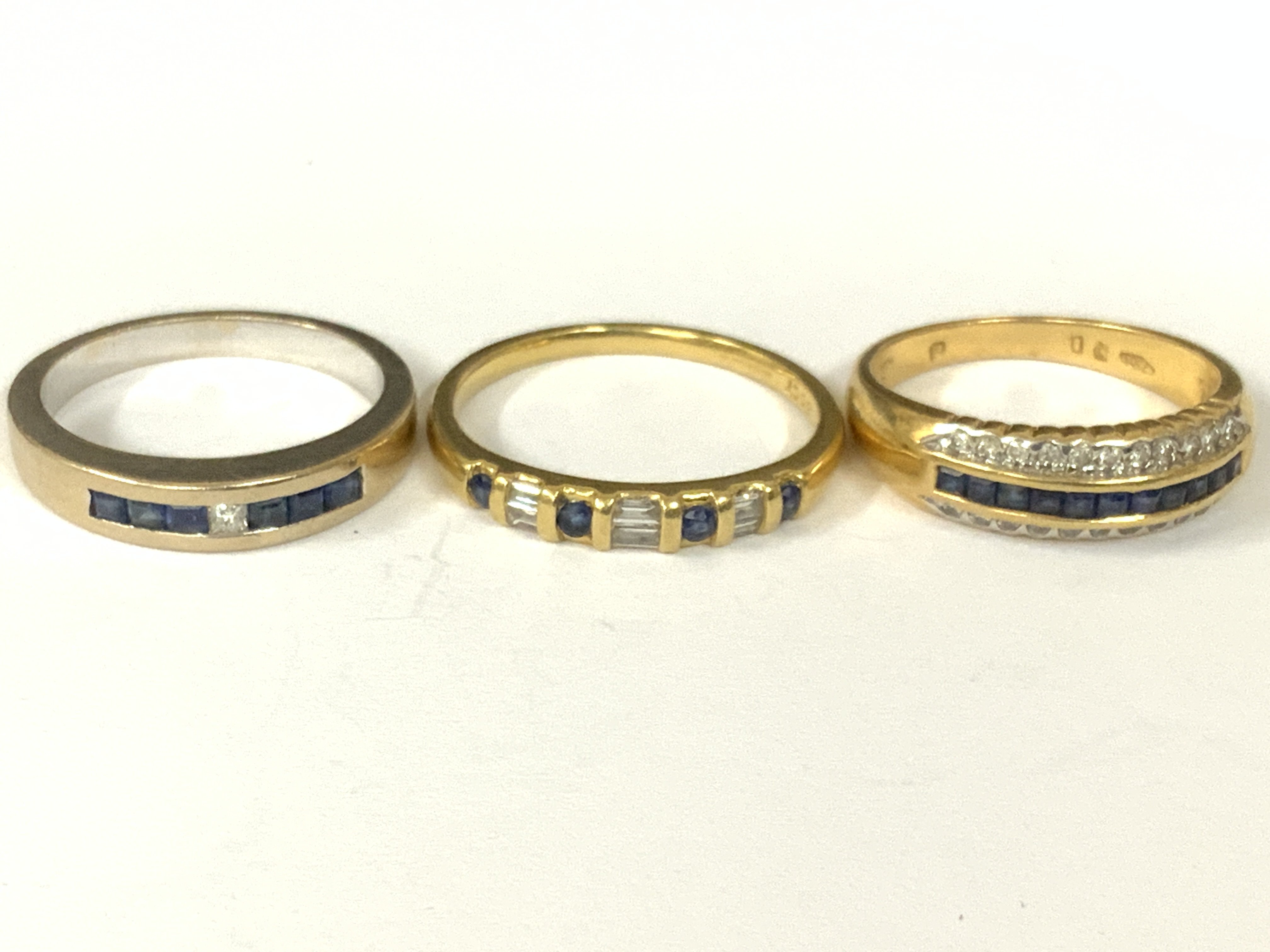 Three 18ct gold sapphire/diamond half hoop rings (x1 white gold). Approx ring size M,N,Q. Approx 11.8g. Postage category A