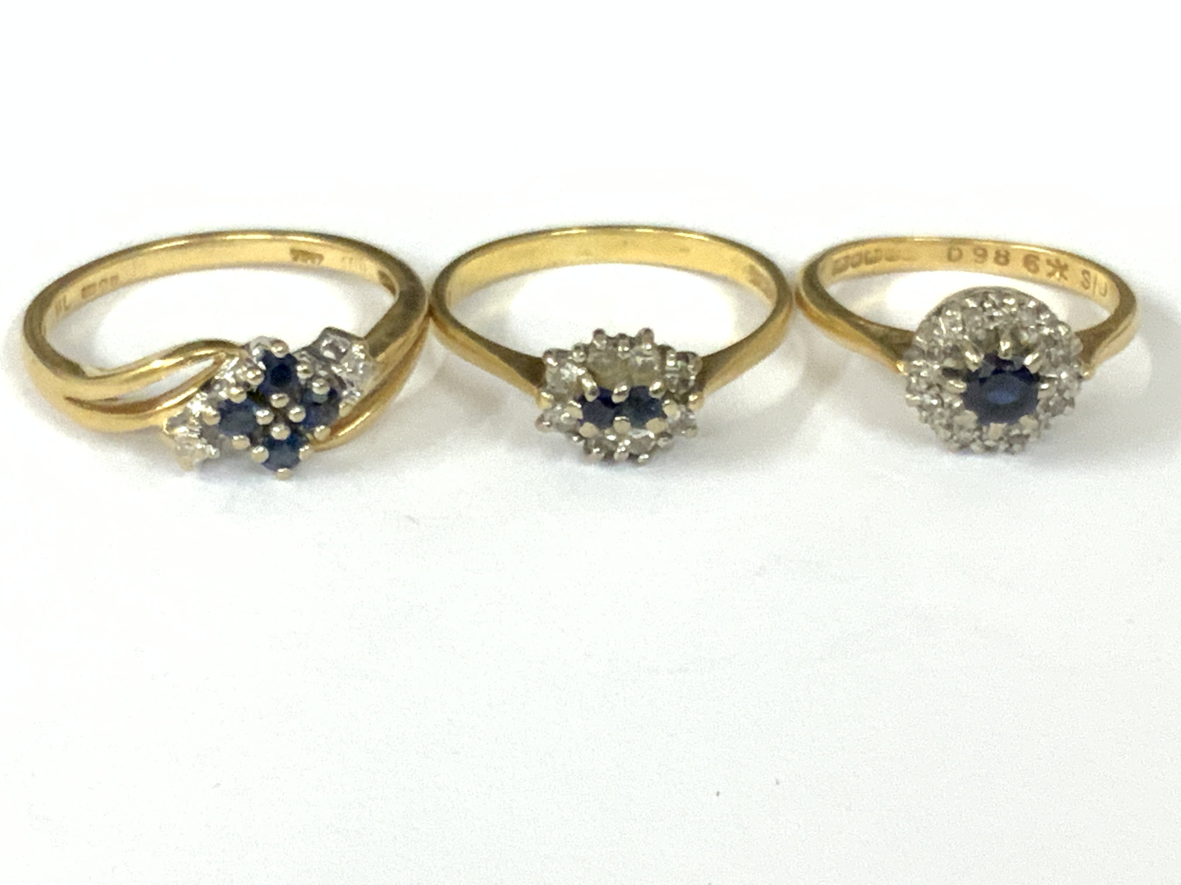 Three 18ct gold sapphire / diamond cluster rings. Approx ring size I,N,P. Approx 8.9g. Postage category A