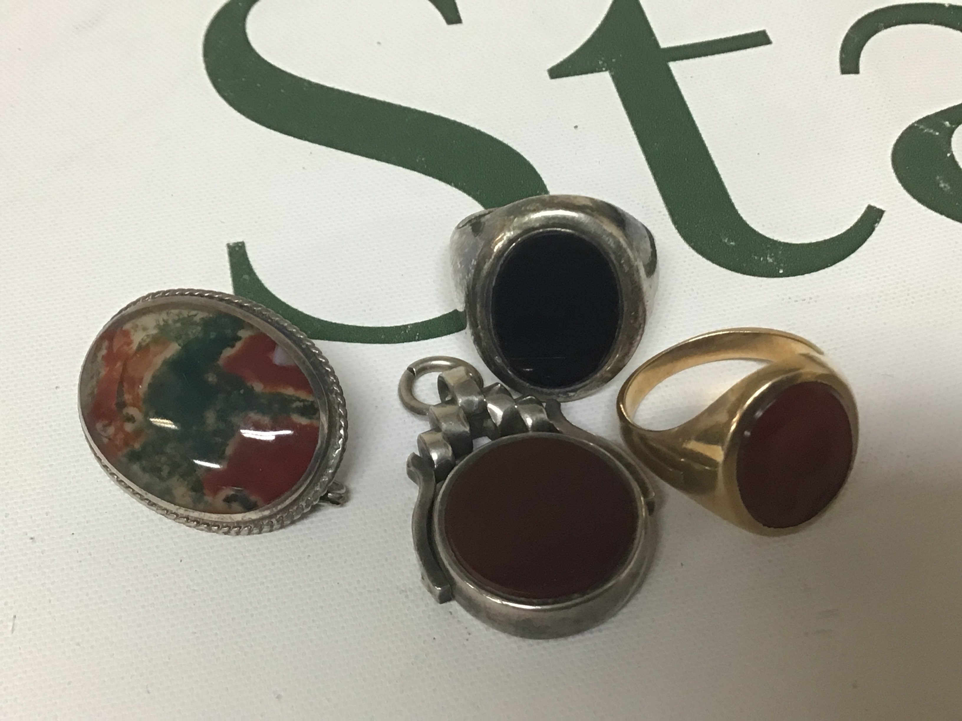 A Gents ring set with an intaglio unmarked weight 4.8g approximately a silver ring moss agate polished brooch and a swivel fob (4)
