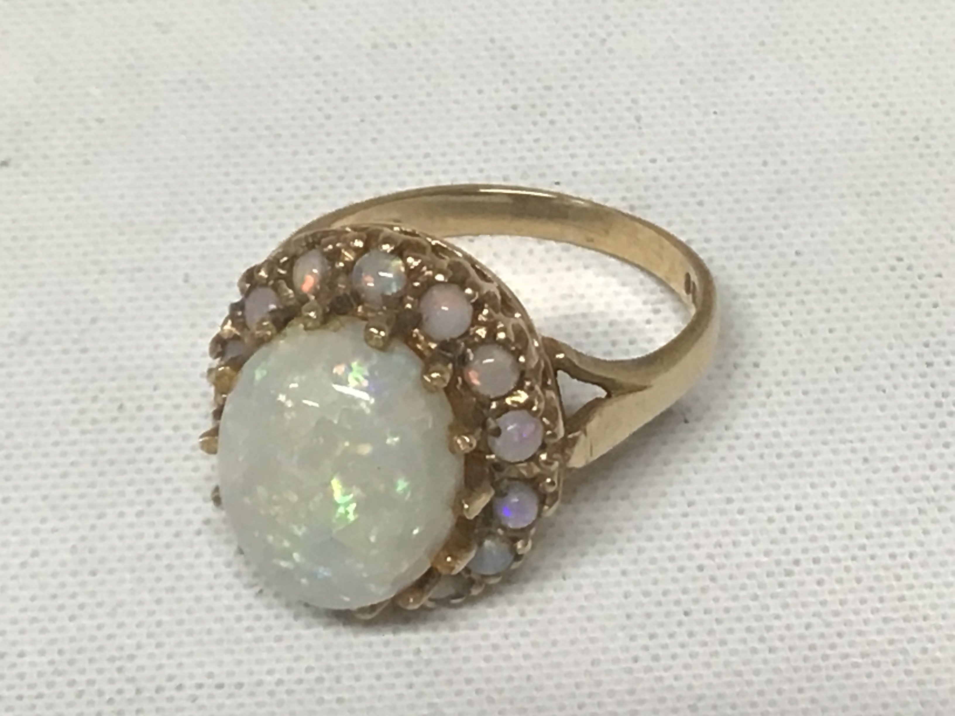A 9carat gold ring set with a good sized opal flanked by smaller opals central stone with some surface cracks. Weight 4.9g