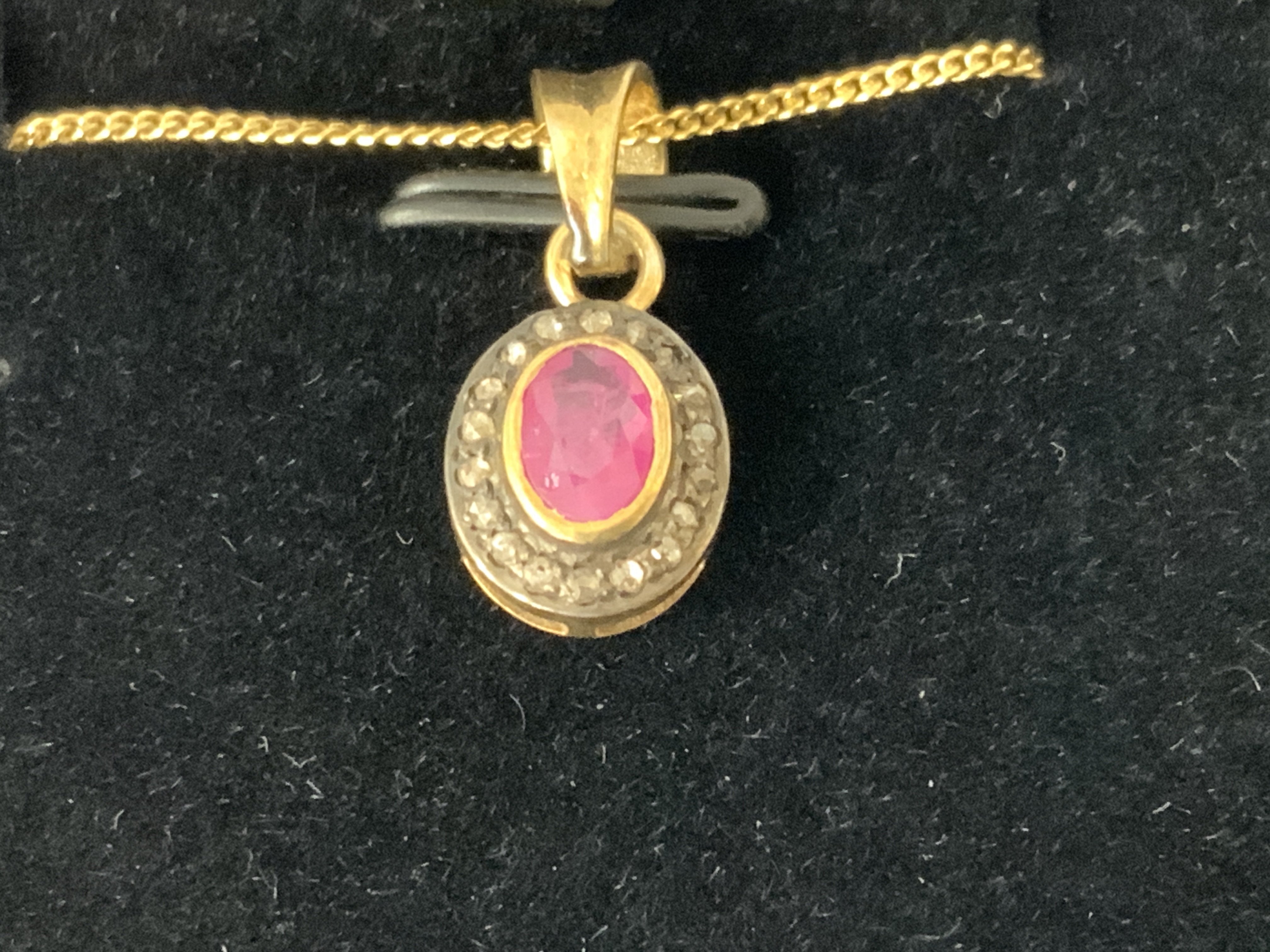 Oval ruby and RBC diamond halo pendant in gold plated silver, boxed. Ruby 0.40ct approx. Diamonds 0.12ct approx. Postage category A.