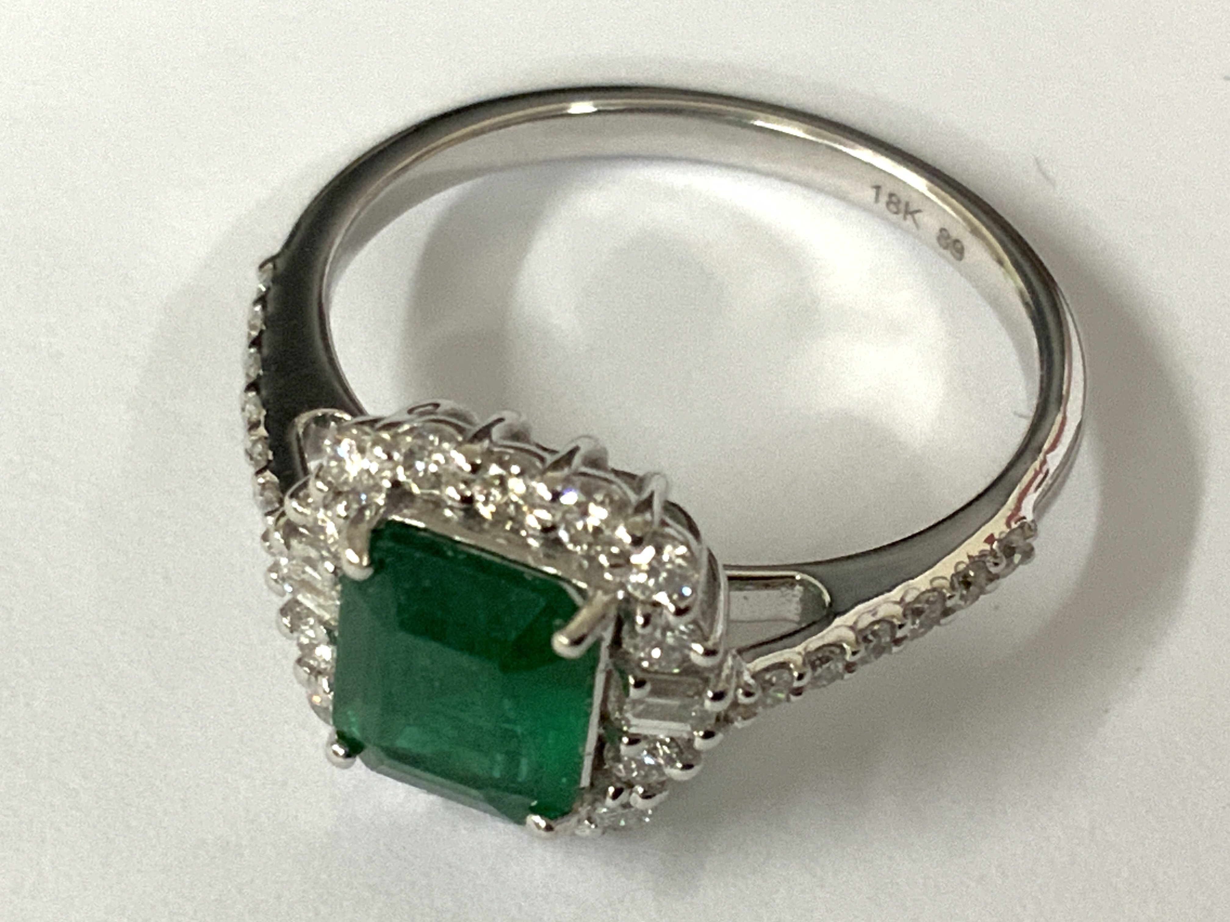 18ct white gold step cut emerald ring within an RBC and baguette cut diamond border, with further RBC diamonds to the shoulders. Emeralds 1.13ct. Diamonds 0.47ct. Approx ring size N/O. Postage category A.